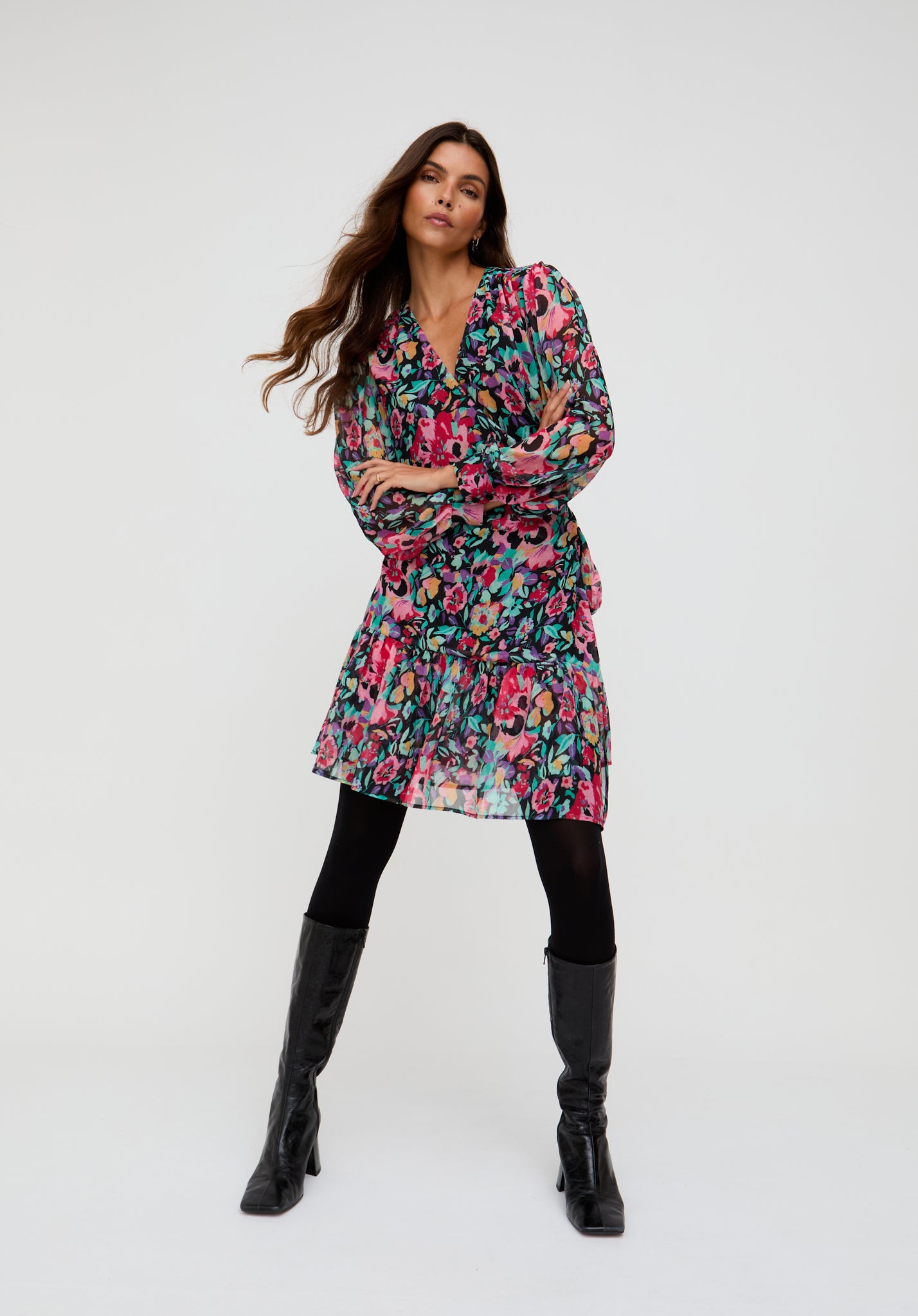 Woman wearing a floral dress and black knee-high boots on a white background
