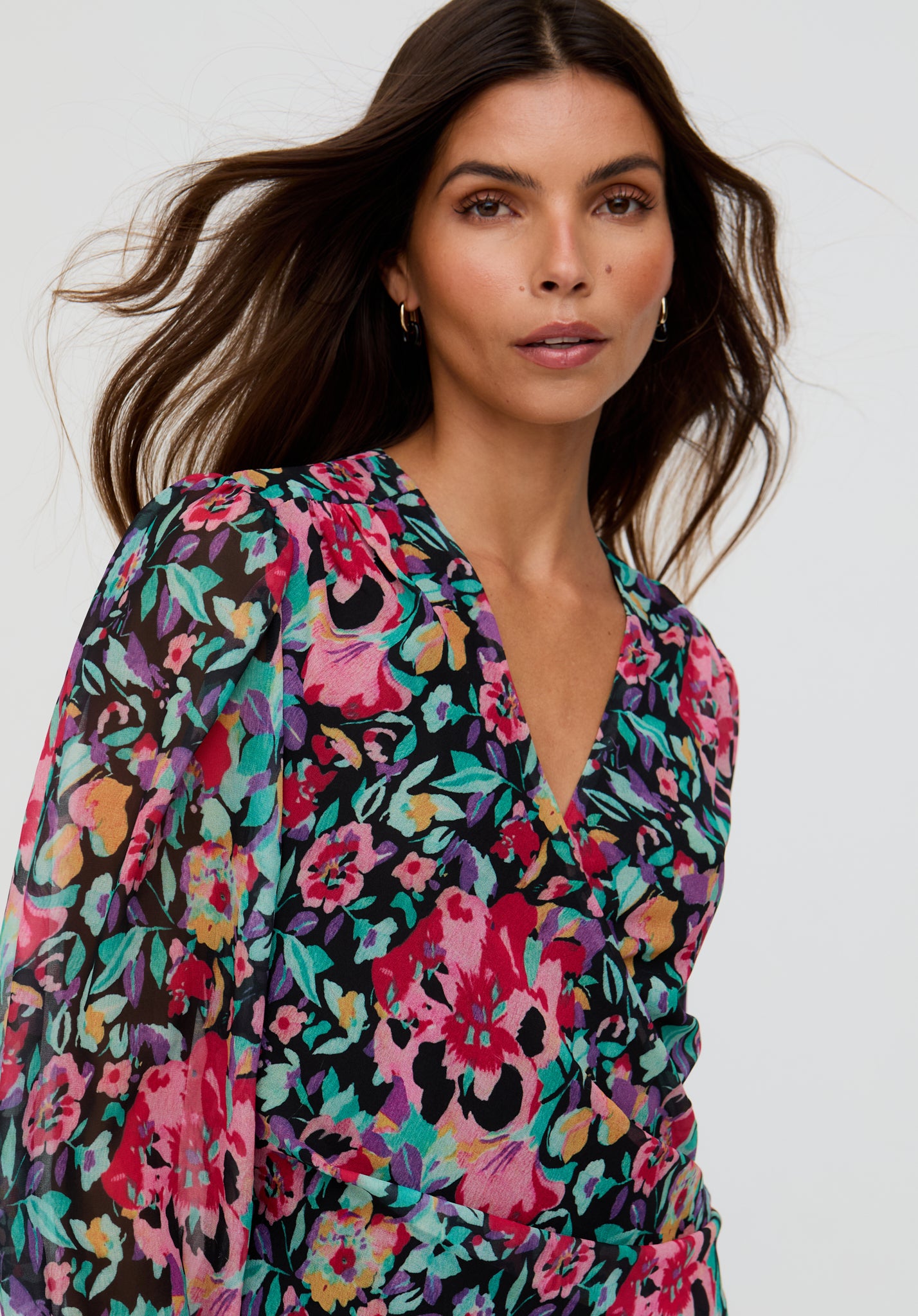 Woman wearing a colorful floral dress against a white background