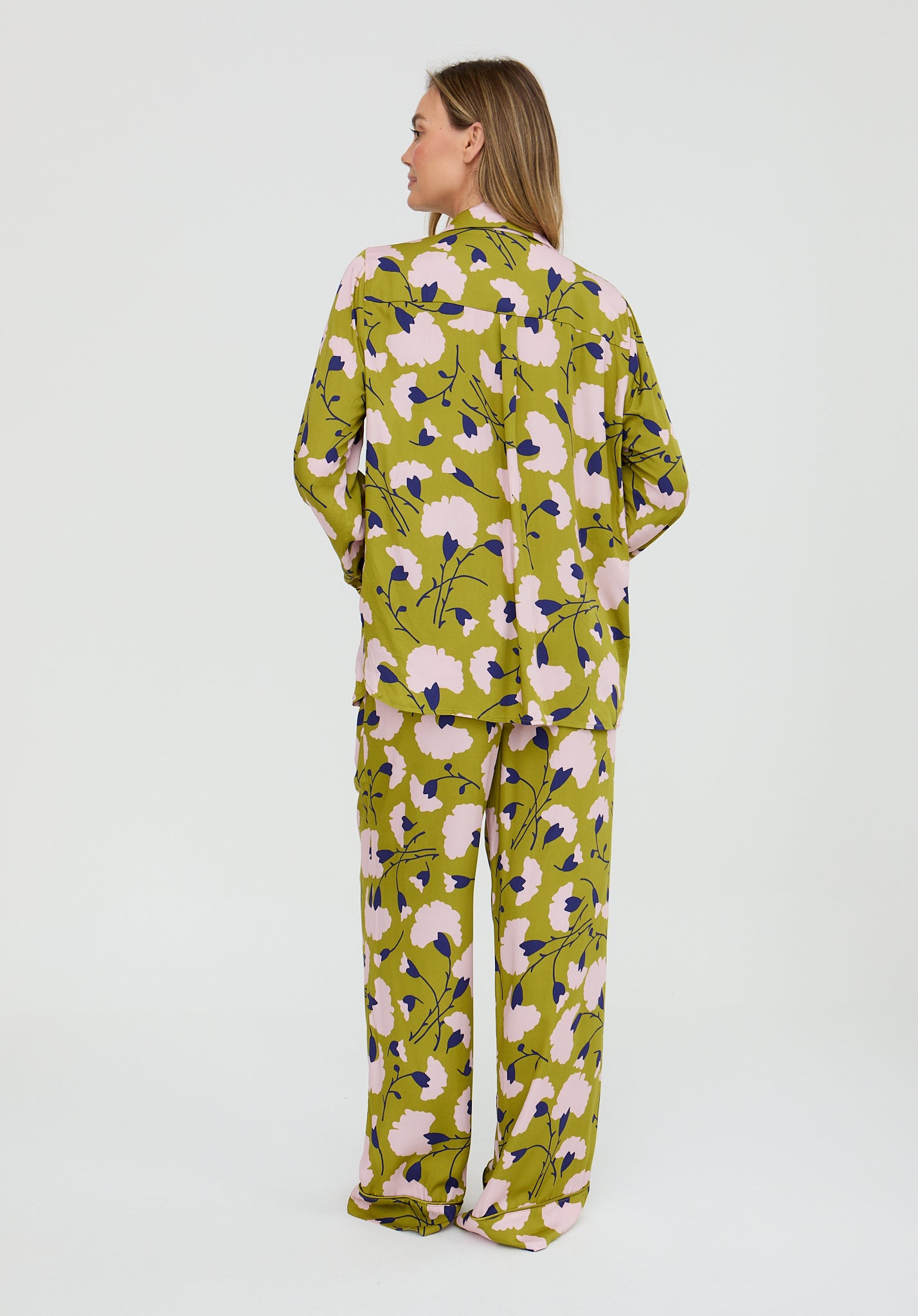 Woman wearing a green floral pajama set on a white background