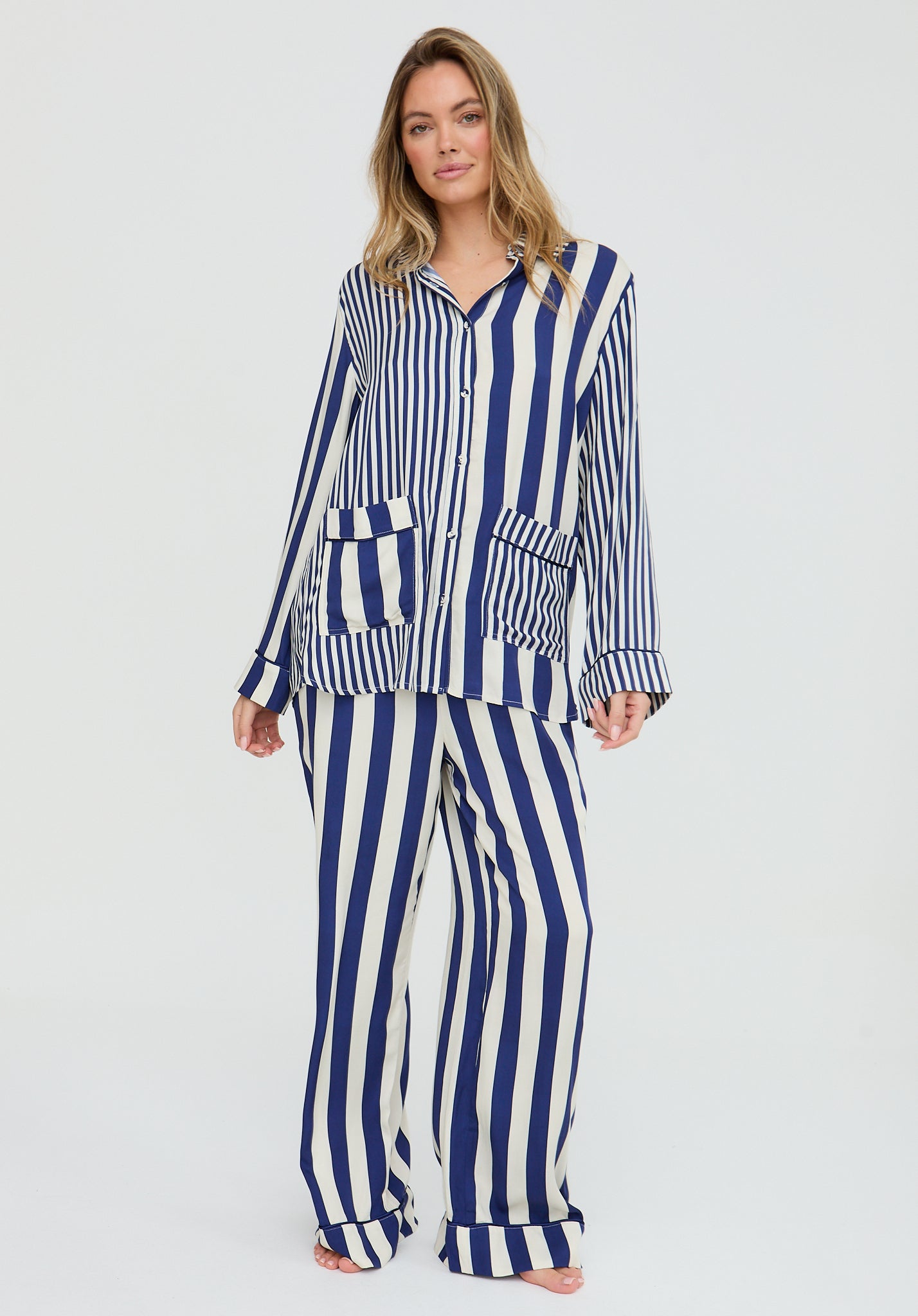 Woman wearing a blue and white striped pajama set on a light gray background