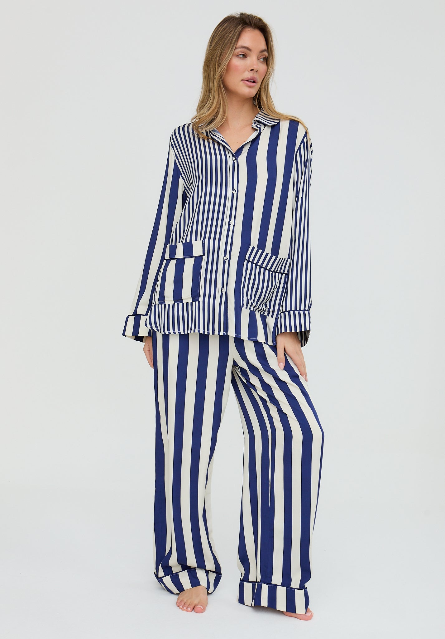 Woman wearing a blue and white striped pajama set on a white background