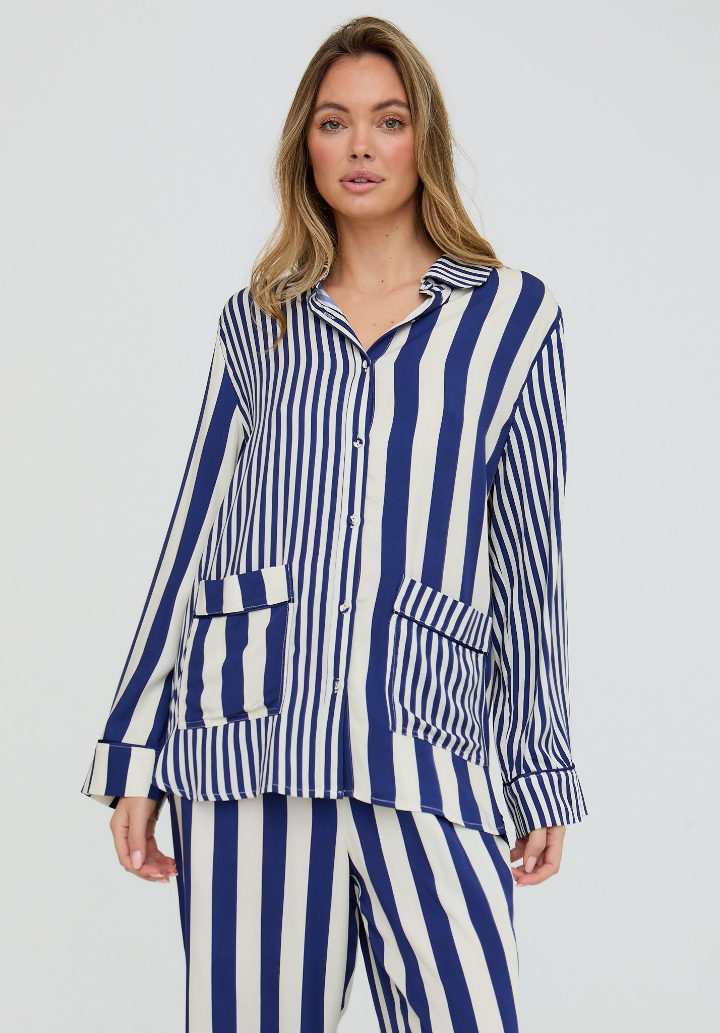 Woman wearing a blue and white striped pajama set on a plain background
