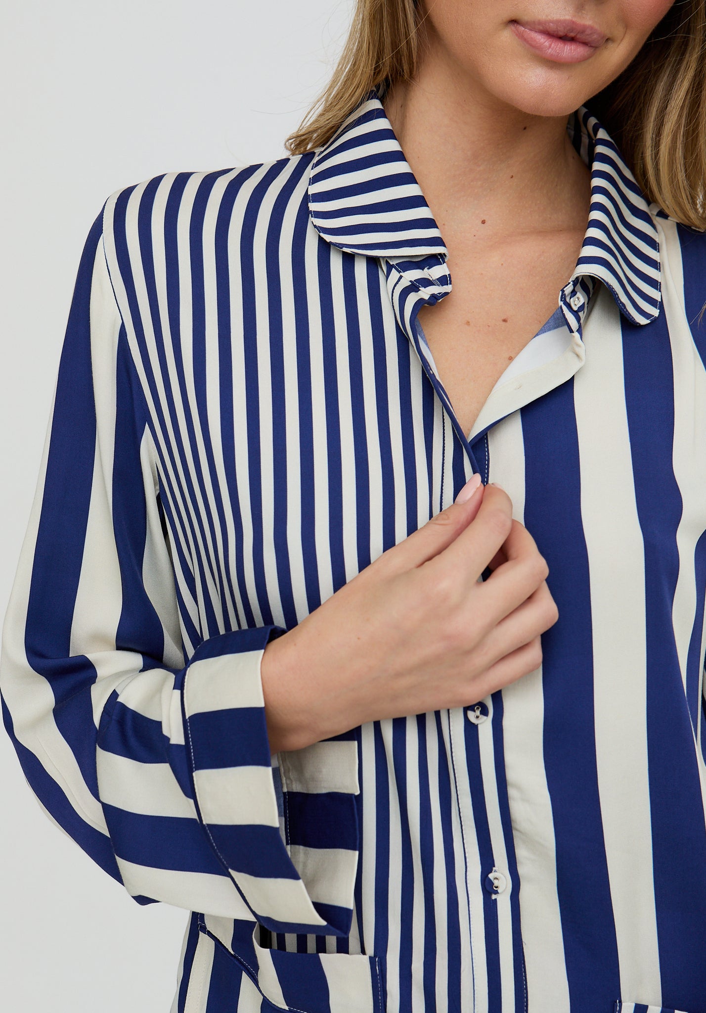 Woman wearing a blue and white striped shirt against a plain background