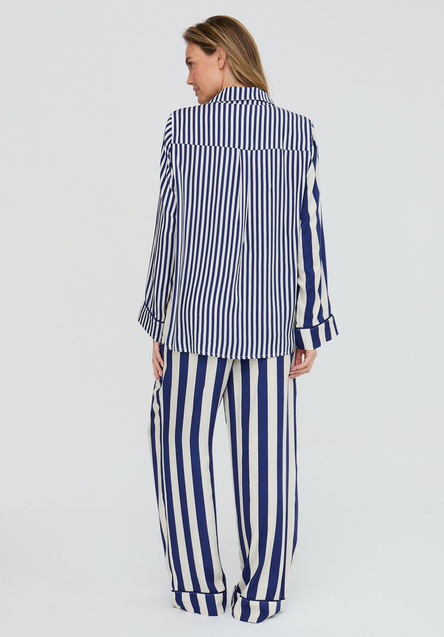 Woman wearing a blue and white striped shirt and pants on a light gray background