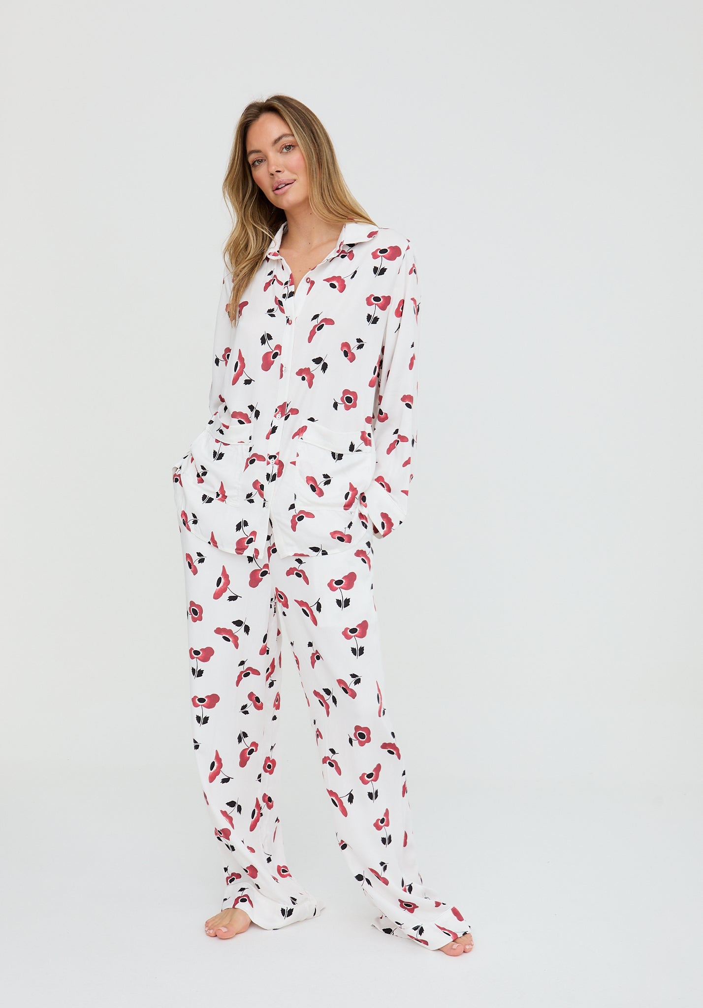 Woman wearing a white onesie with red and black floral pattern on a white background