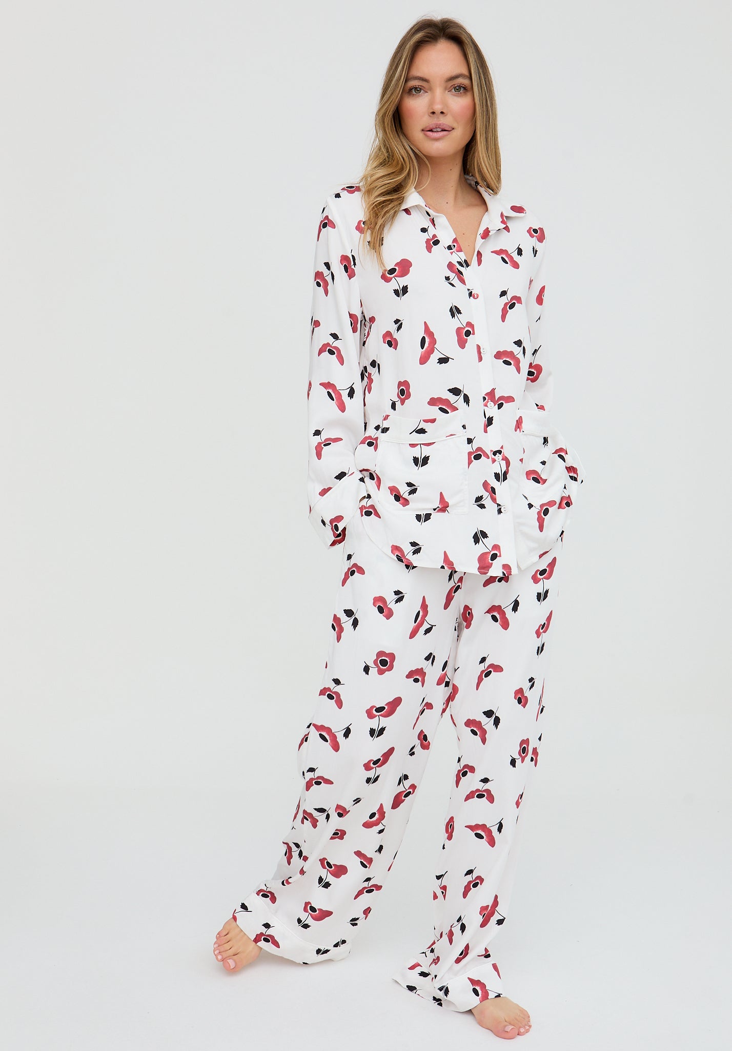 Woman wearing a white onesie with red and black patterns on a plain background