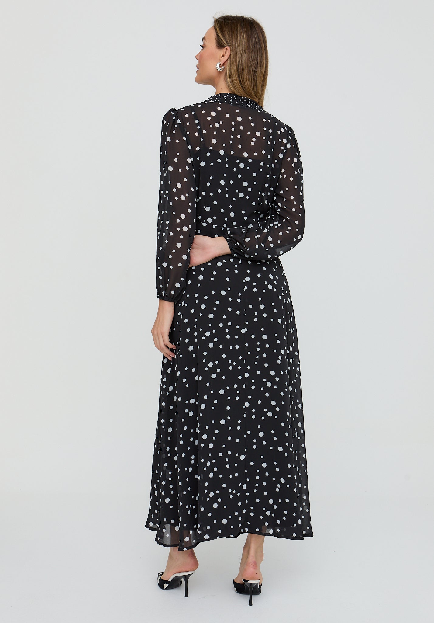Woman wearing a black dress with white polka dots on a white background