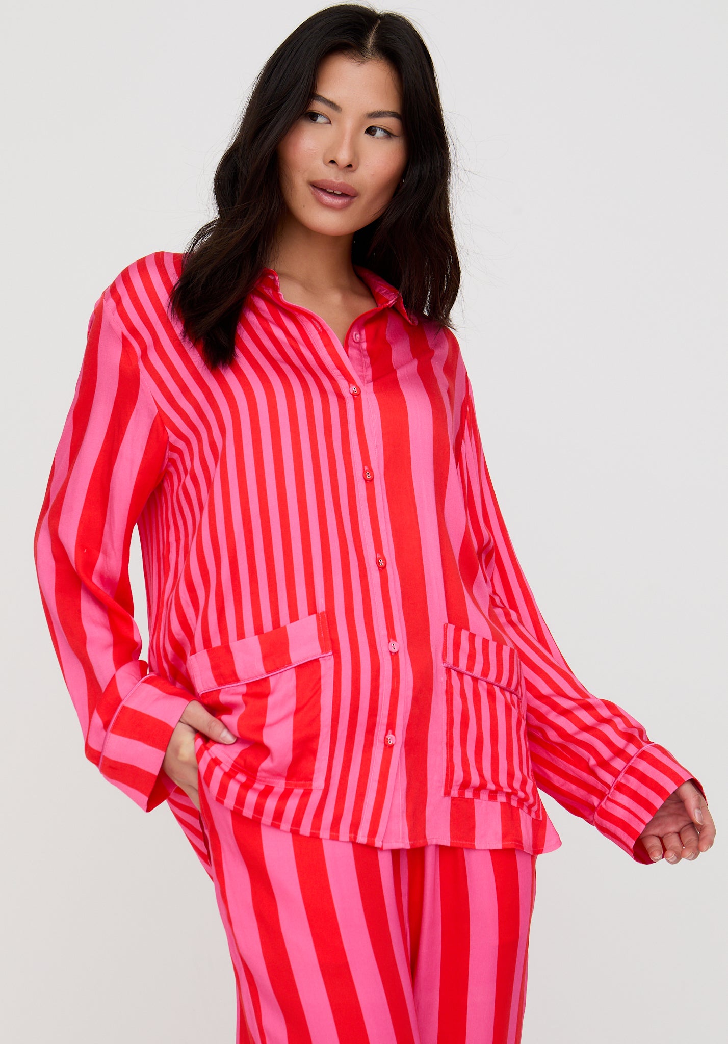 Woman wearing a red and pink striped pajama set against a white background