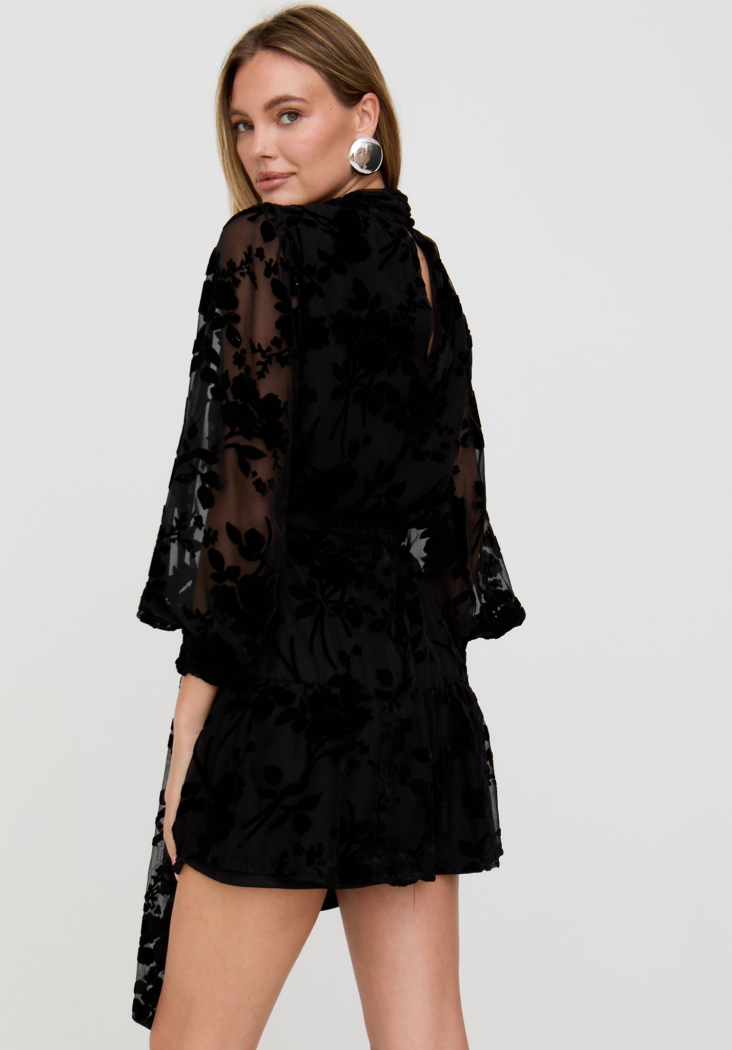 Woman wearing a black lace dress against a plain background