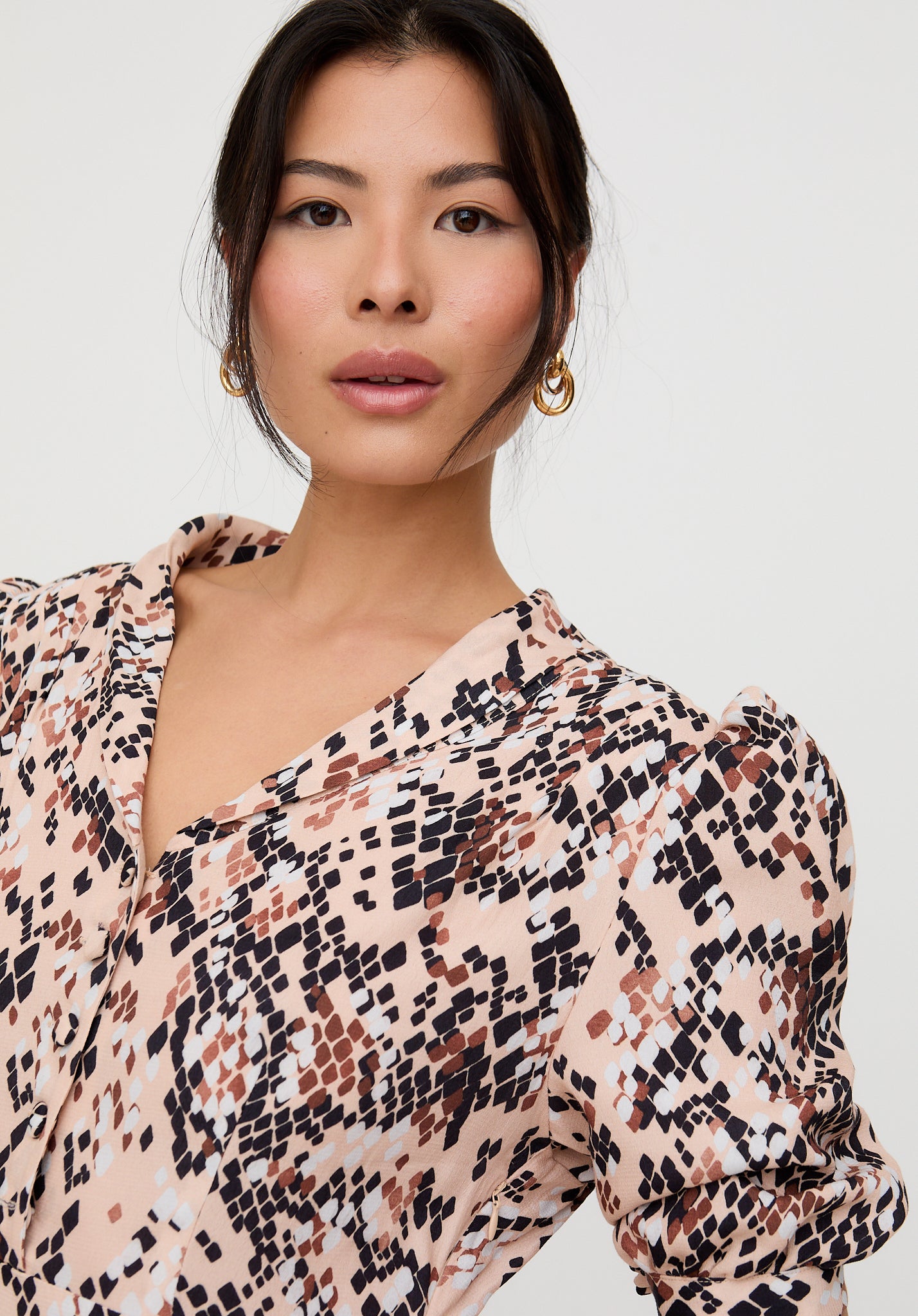 Woman wearing a patterned blouse against a plain background