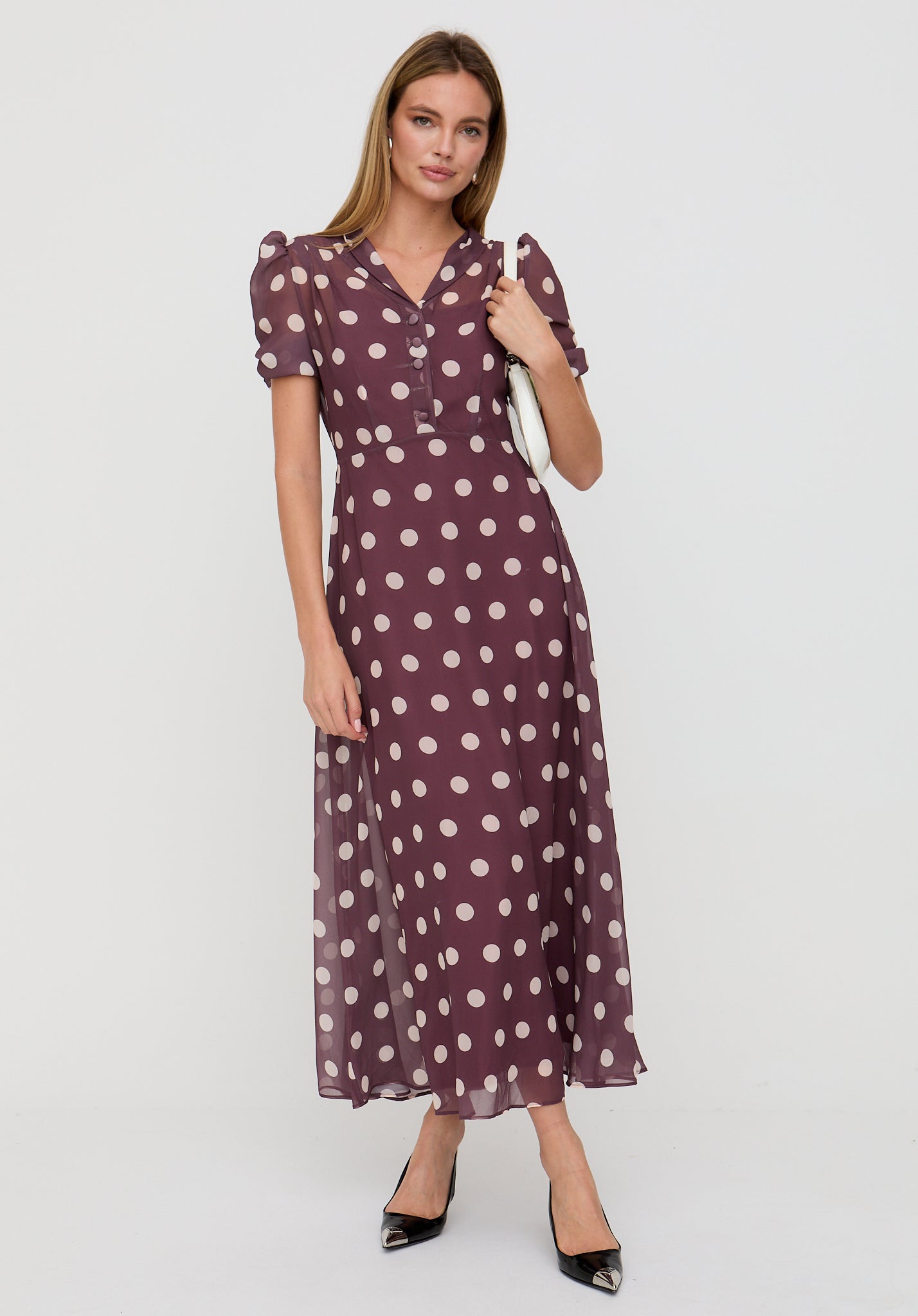 Woman wearing a purple polka dot dress on a white background