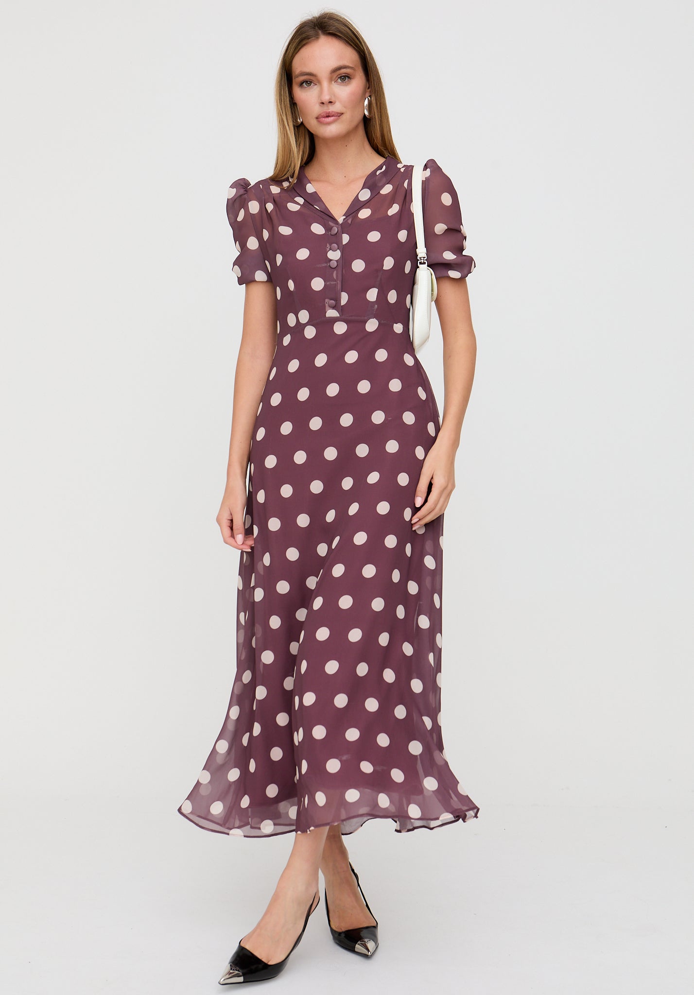 Woman wearing a purple dress with white polka dots on a white background