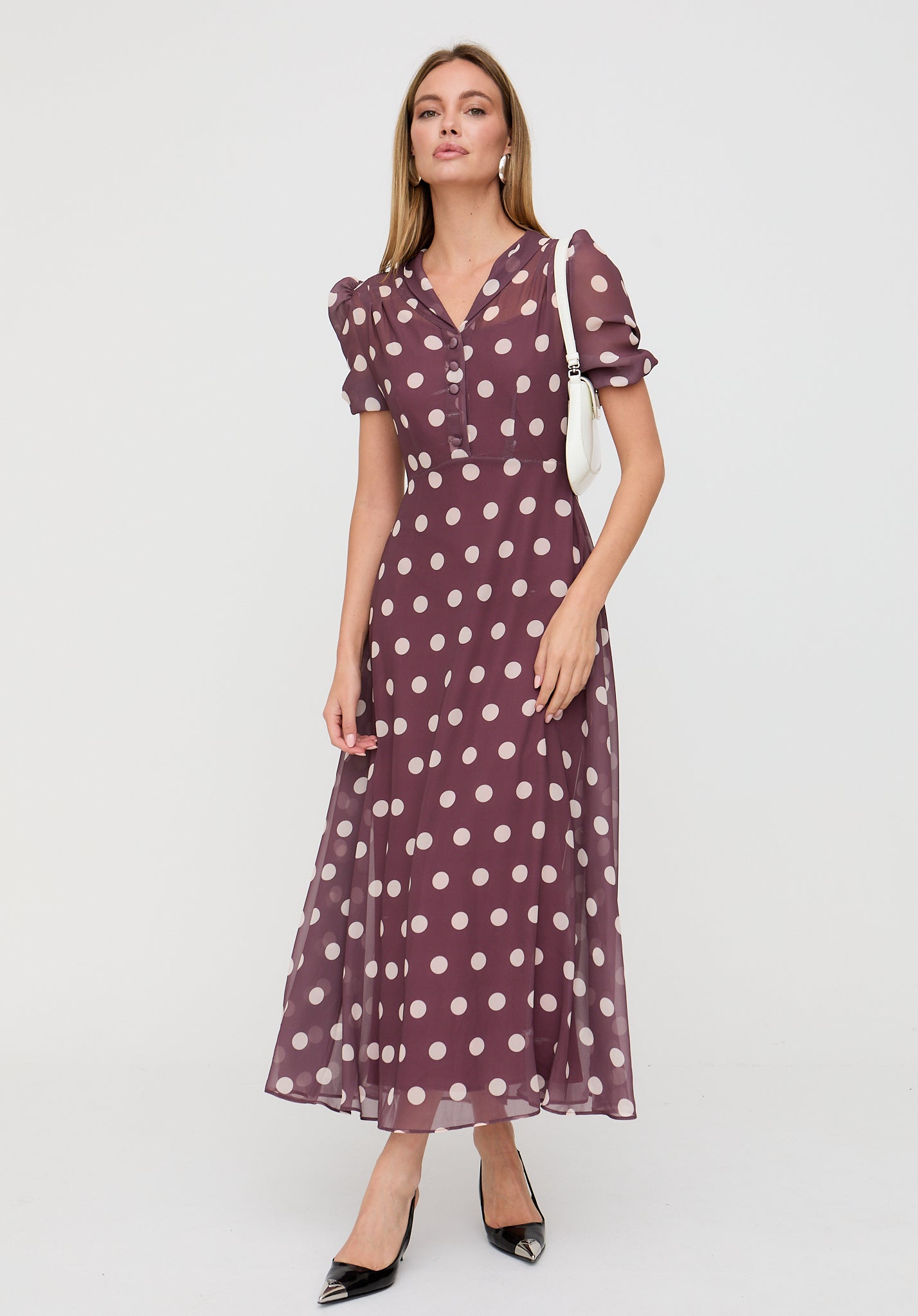 Woman wearing a purple polka dot dress on a white background
