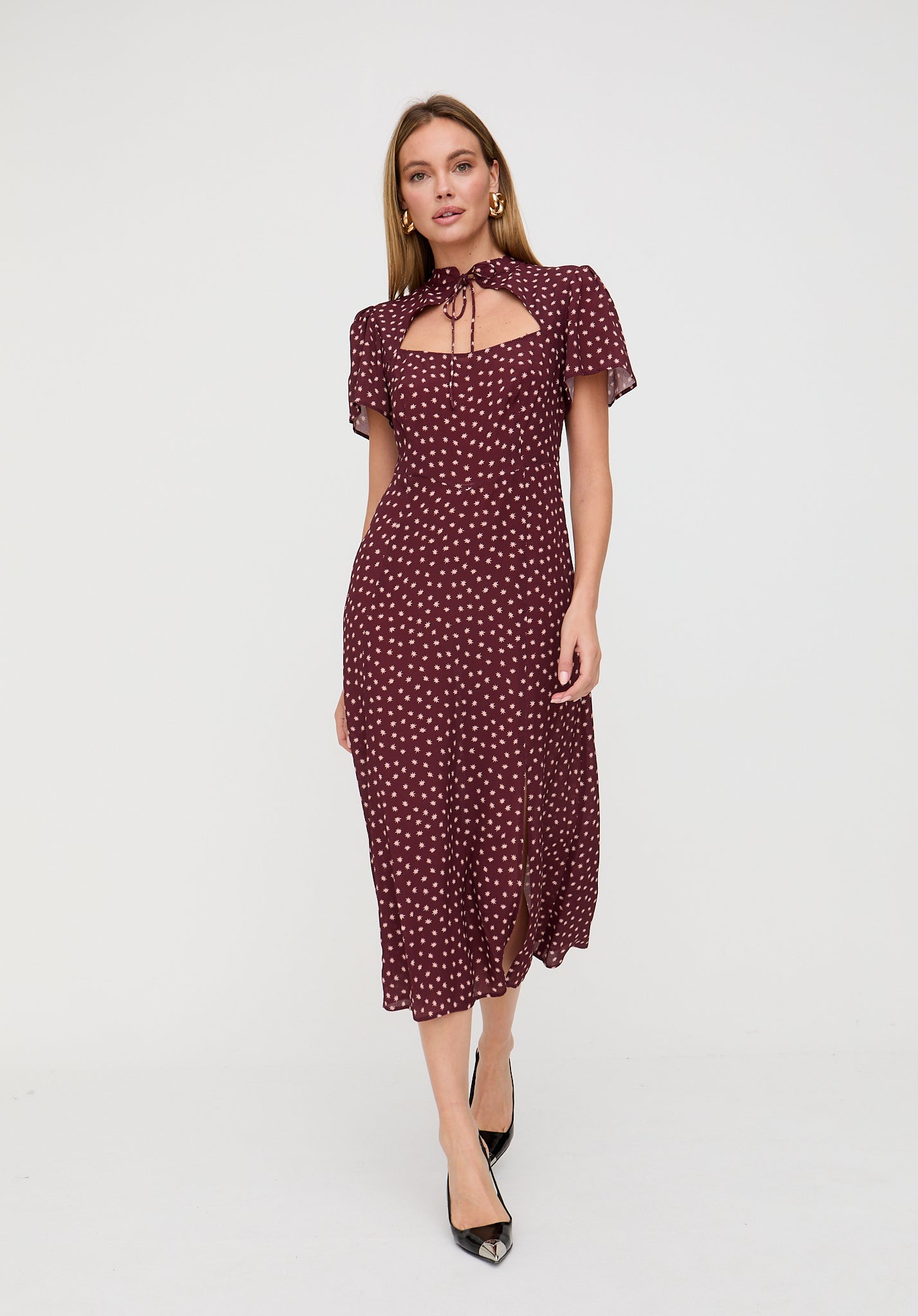 Woman wearing a burgundy polka dot dress on a white background
