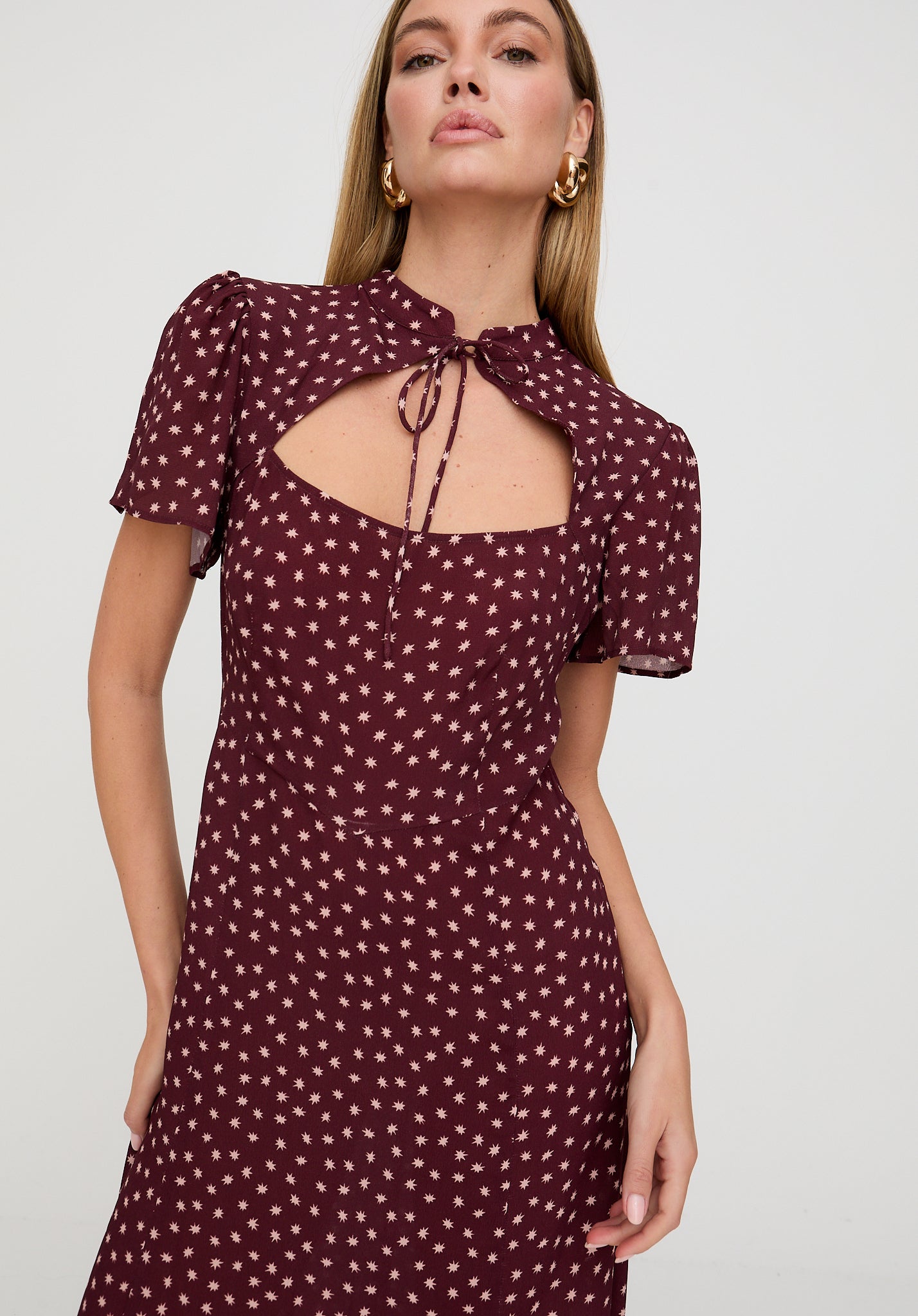 Woman wearing a burgundy dress with white polka dots on a plain background