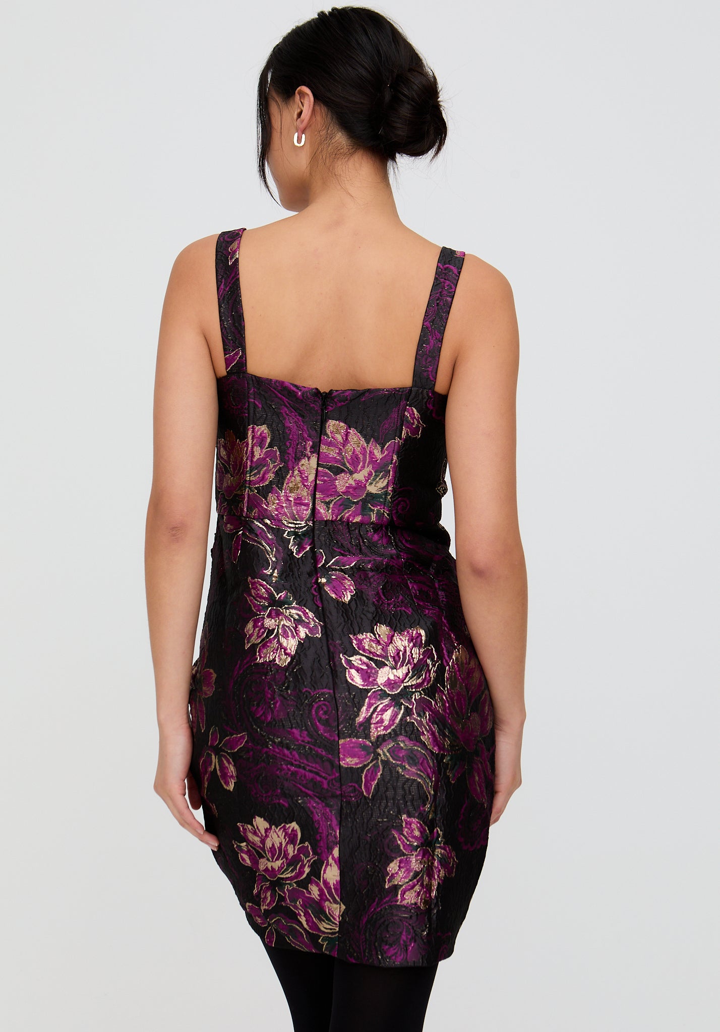 Woman wearing a black dress with purple floral pattern on a white background