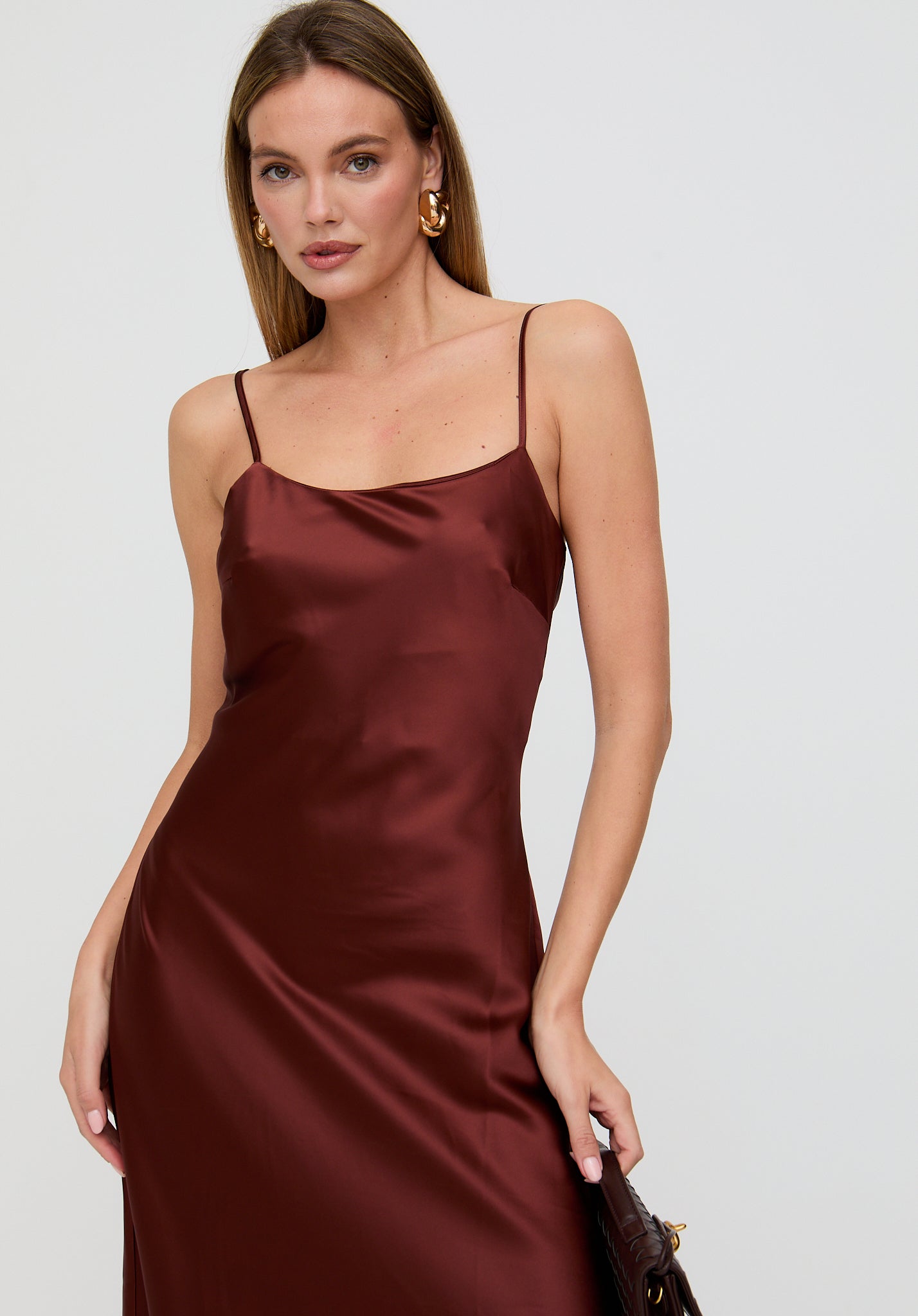 Woman wearing a burgundy satin dress against a white background