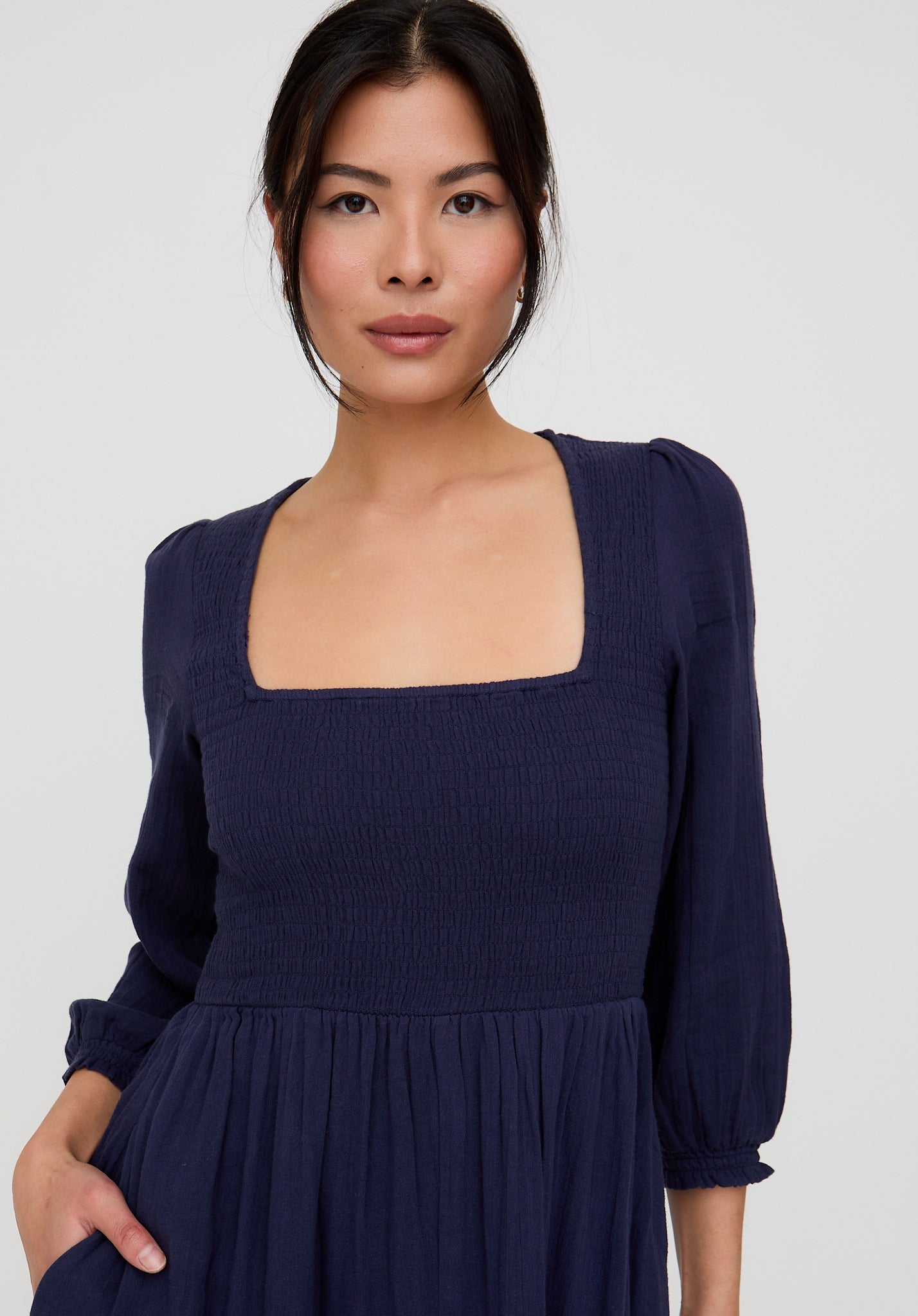 Woman wearing a navy blue dress against a plain background