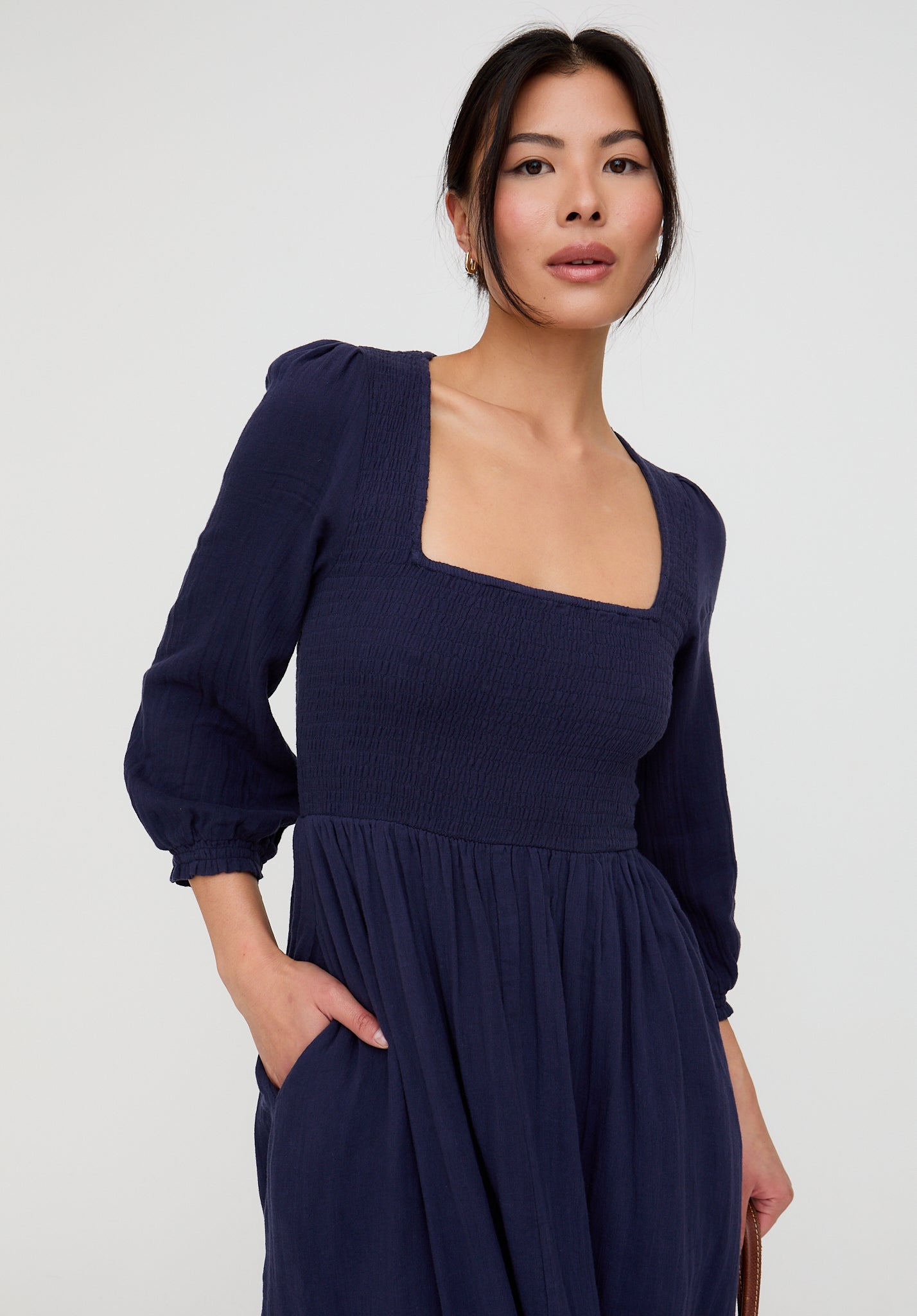 Woman wearing a navy blue dress with a plain background