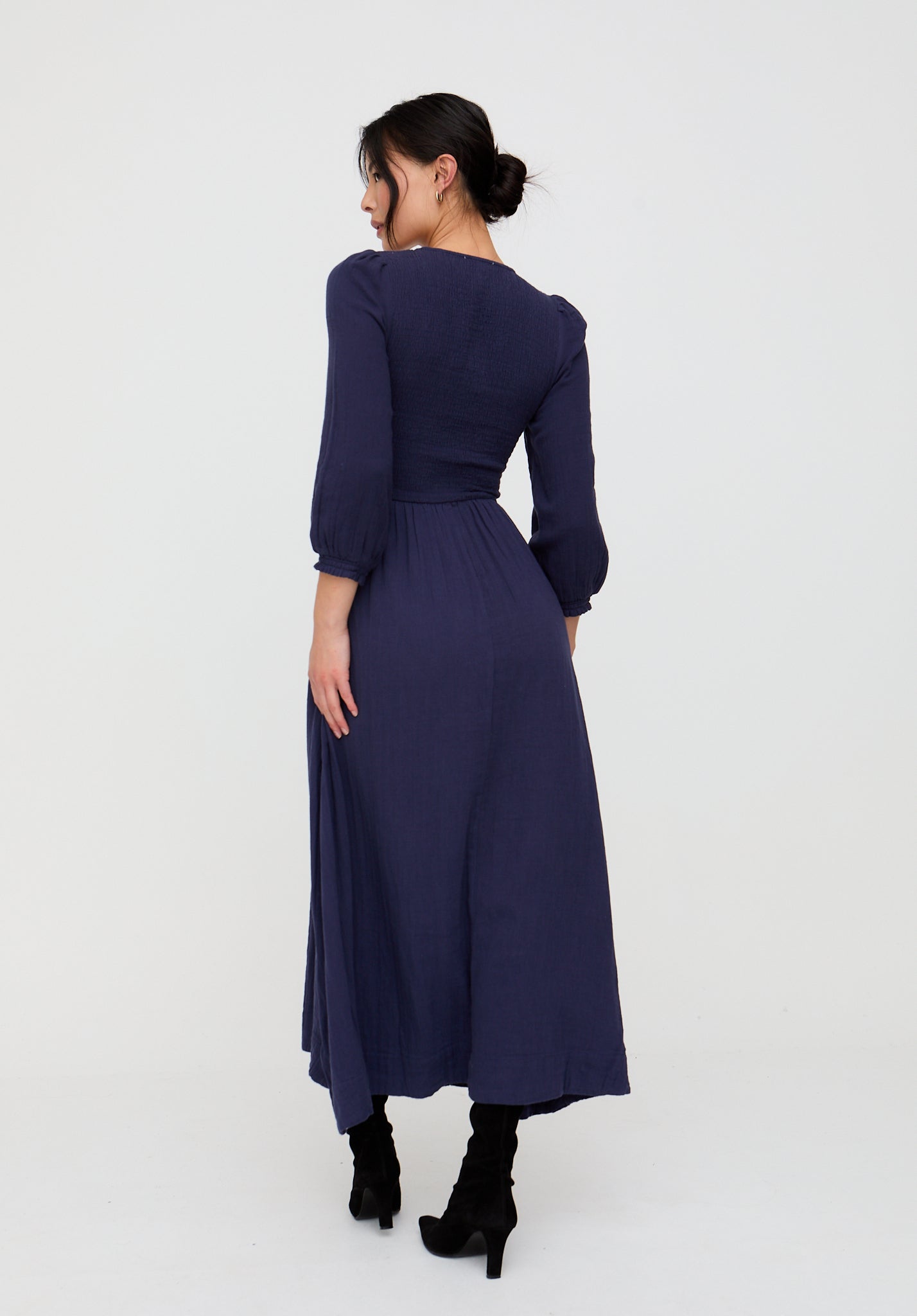 Woman wearing a long navy dress on a white background