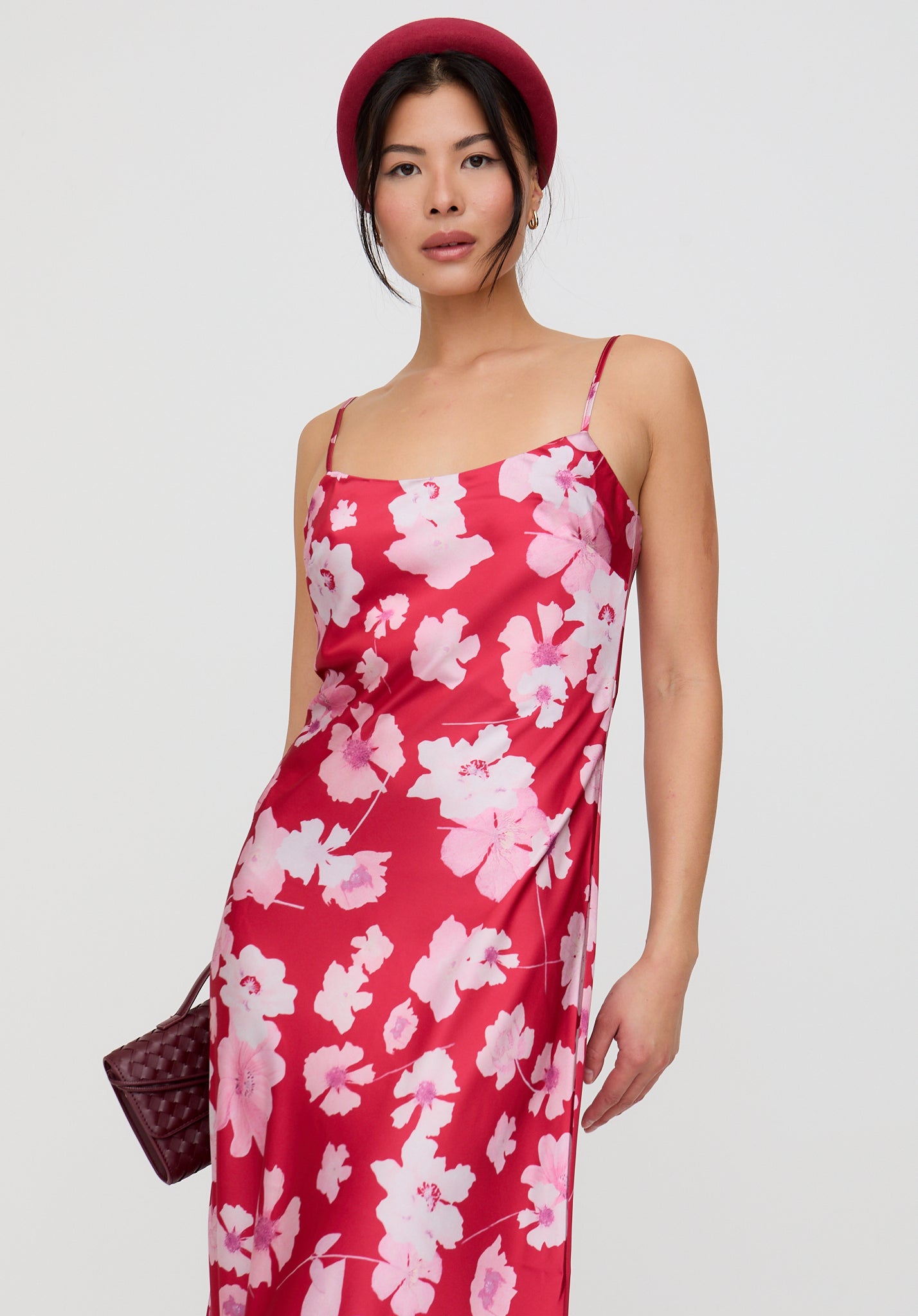 Woman wearing a red floral dress and matching hat on a white background