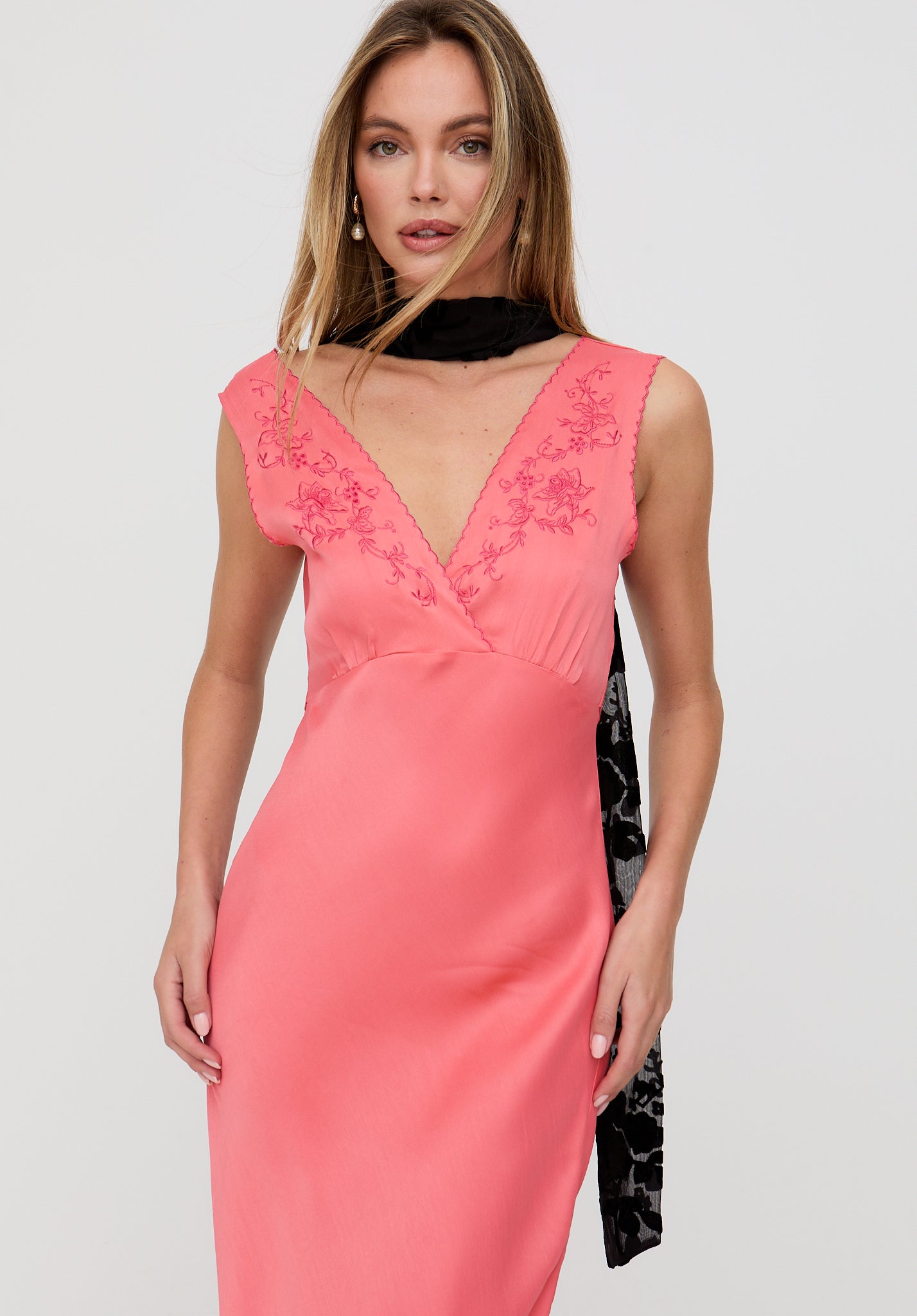 Woman wearing a pink dress with floral lace details on a light gray background