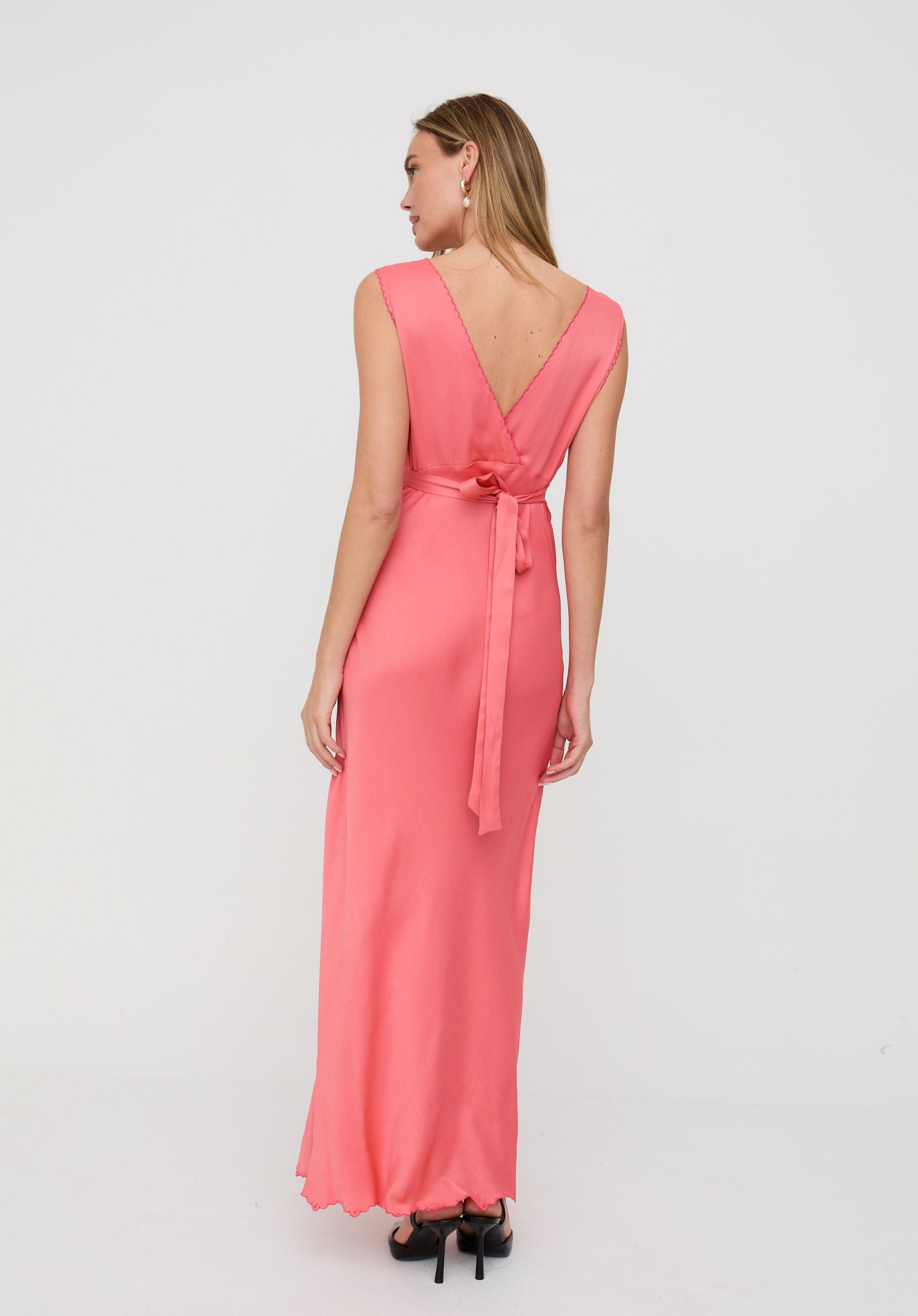 Woman wearing a pink dress with a belt on a white background