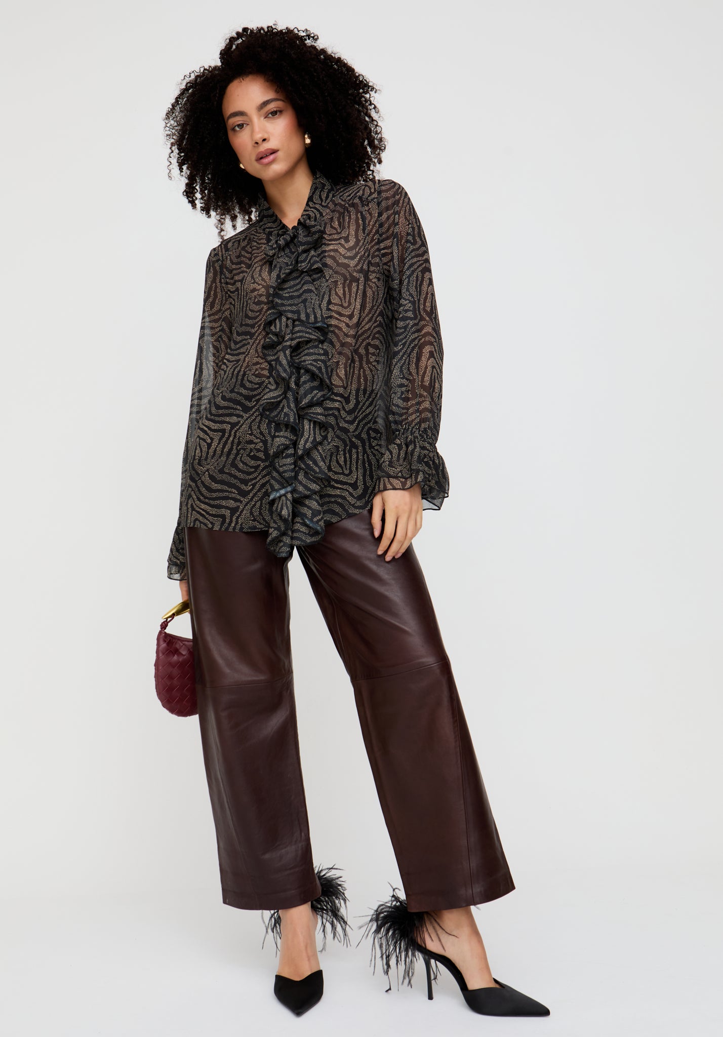 Woman wearing a patterned blouse and brown pants on a white background