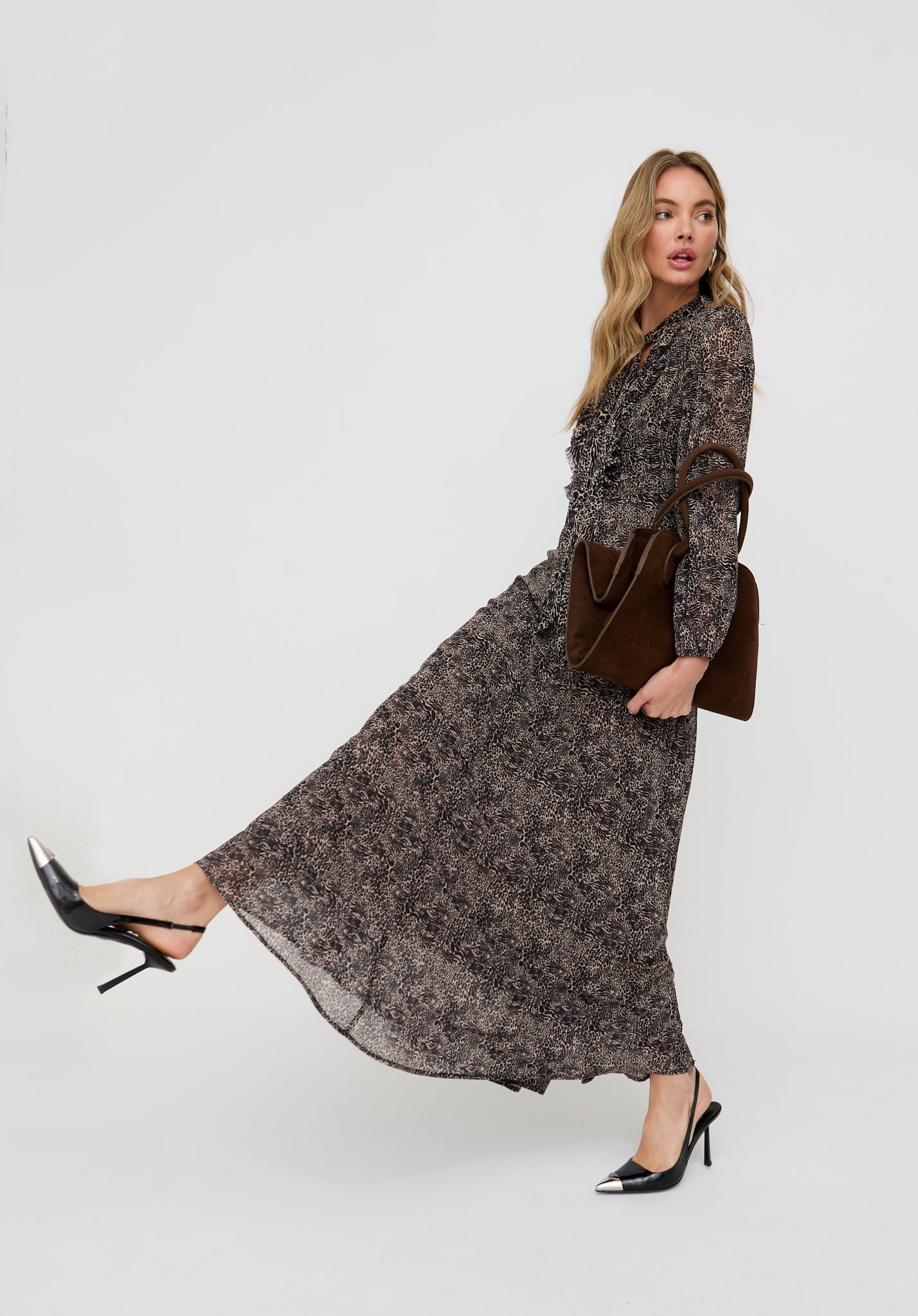 Woman wearing a long floral dress with a brown handbag on a white background