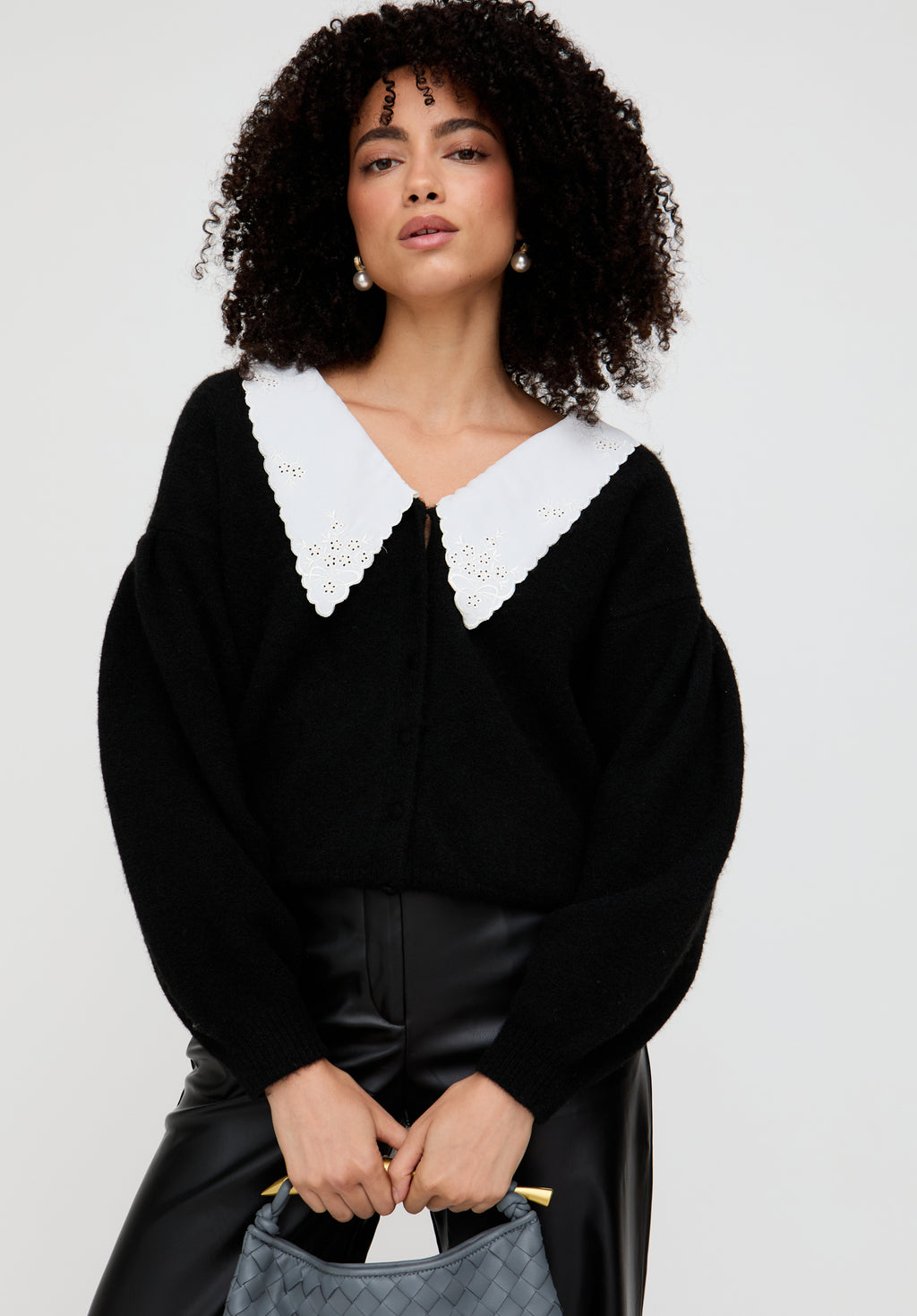 Woman wearing a black blouse with a white collar against a plain background