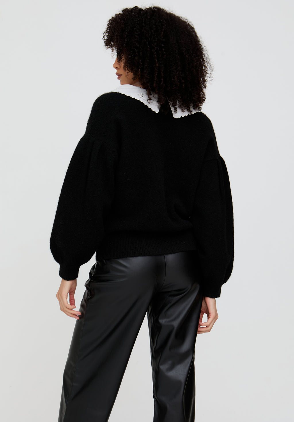 Person wearing a black sweater and black pants on a white background