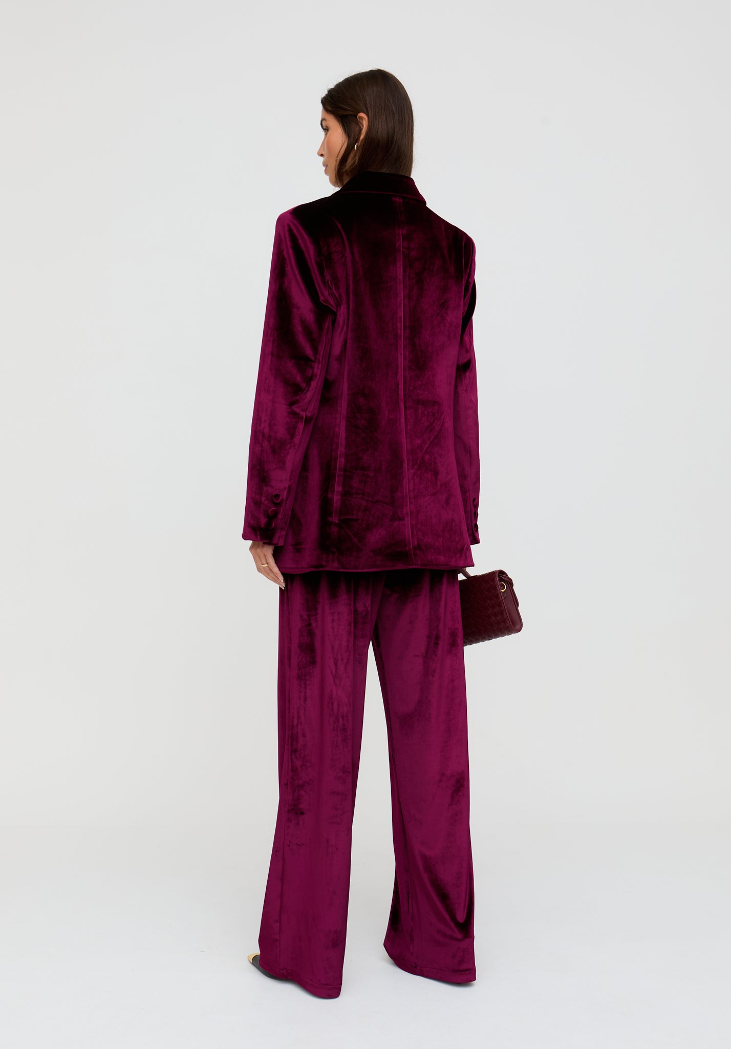 Person wearing a burgundy velvet suit on a white background