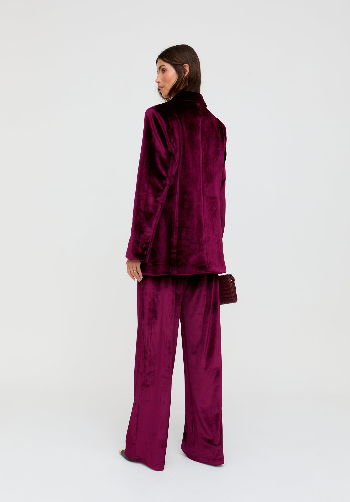 Person wearing a burgundy velvet outfit on a white background