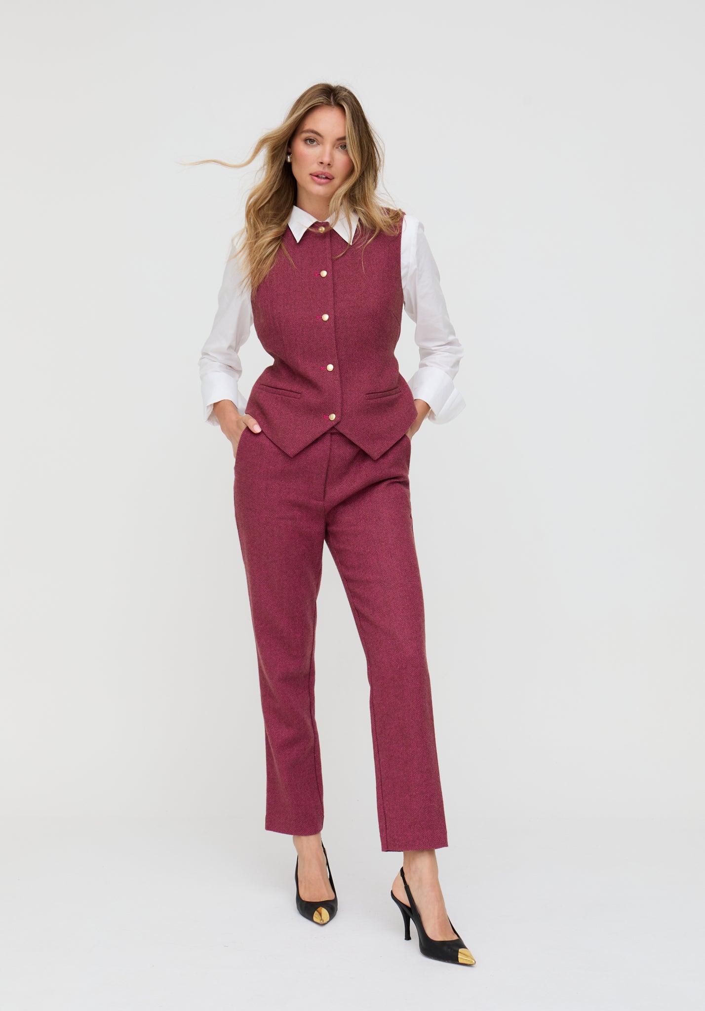 Woman wearing a pink suit with a white shirt on a light gray background
