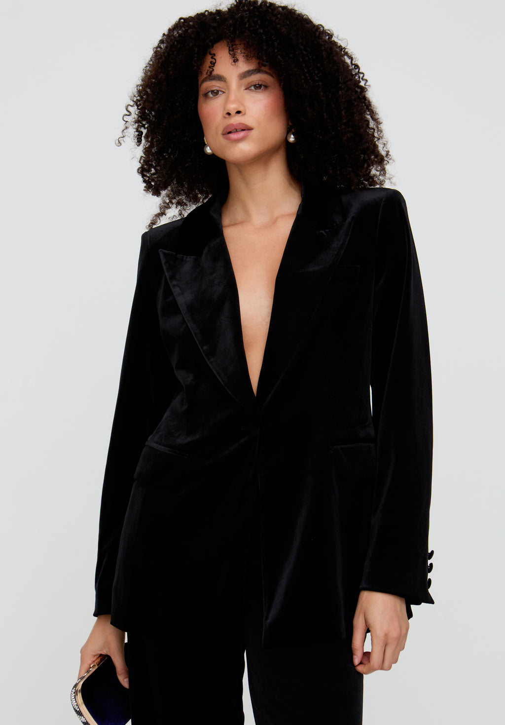 Woman wearing a black velvet suit against a light gray background