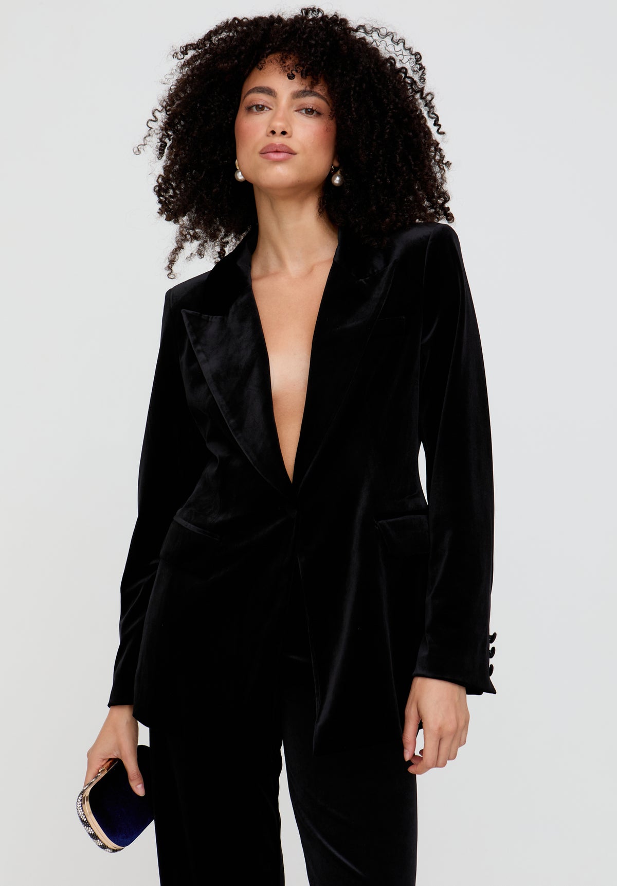 Woman wearing a black velvet suit with a plunging neckline on a light gray background