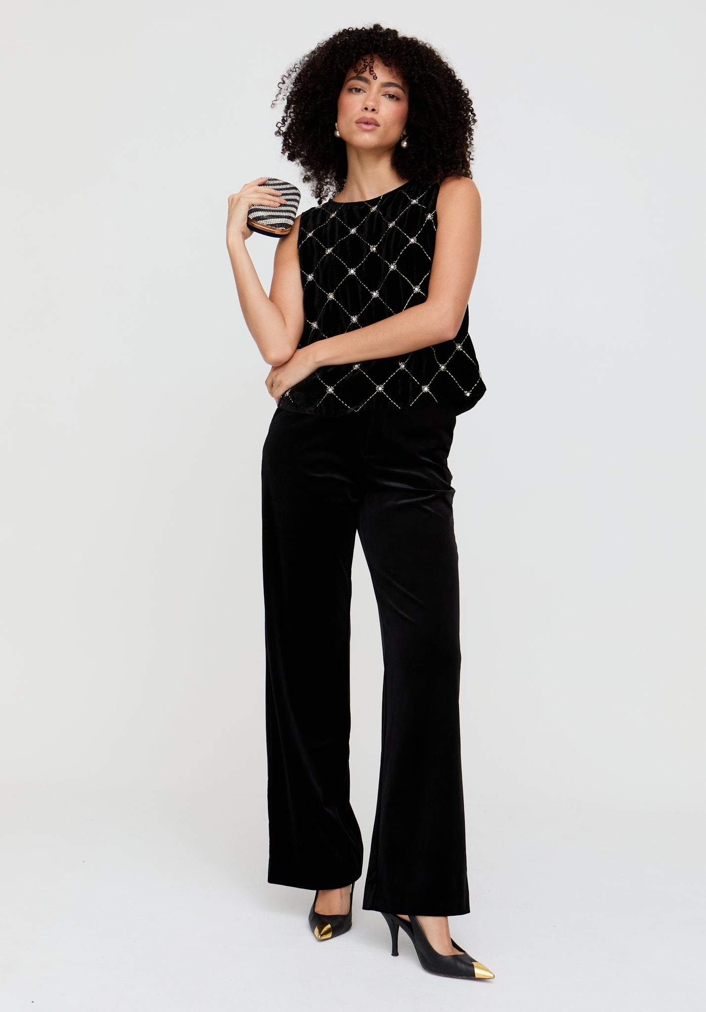 Woman wearing a black outfit with a patterned top and wide-leg pants on a white background