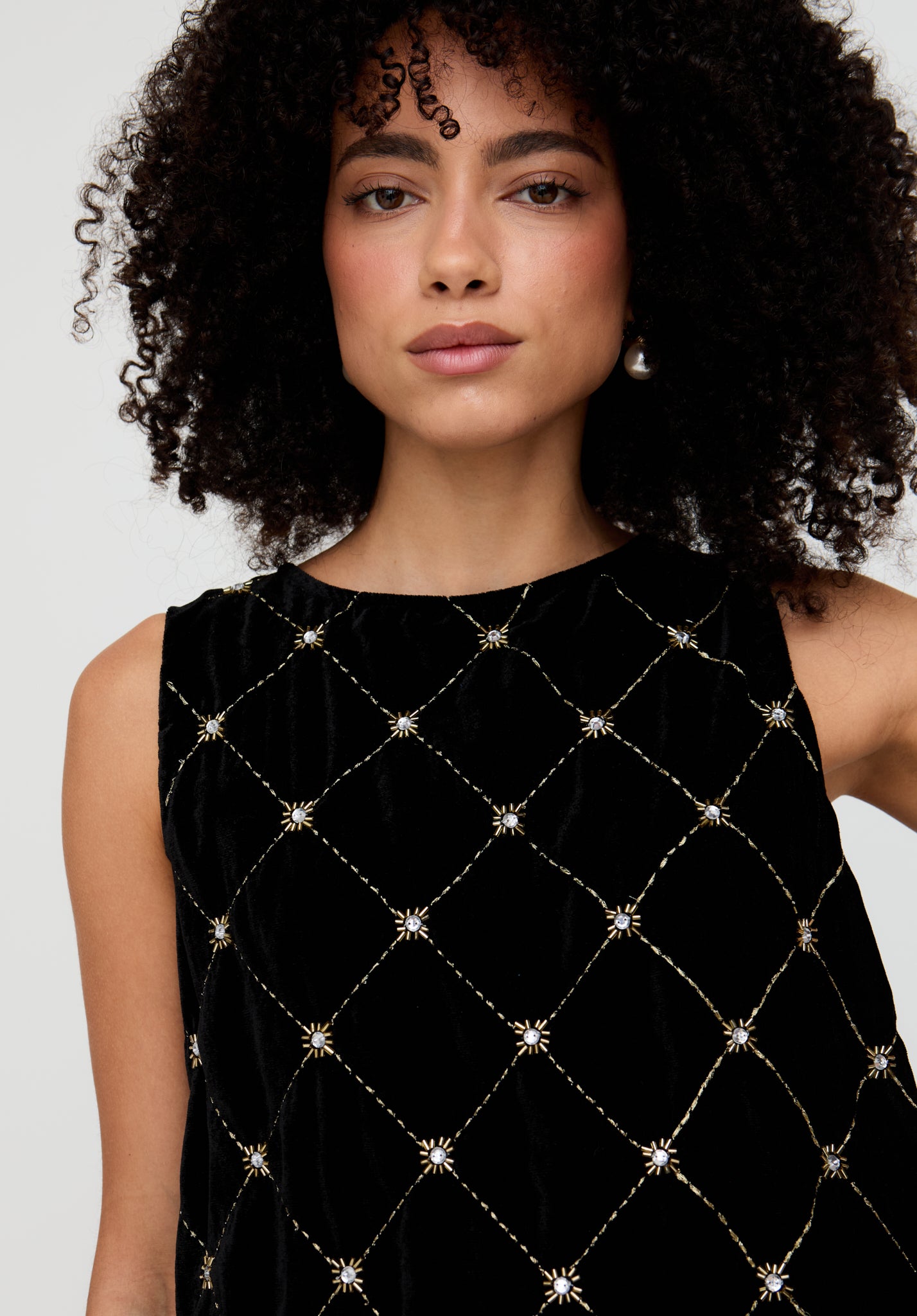 Woman wearing a black dress with diamond pattern and embellishments on a white background