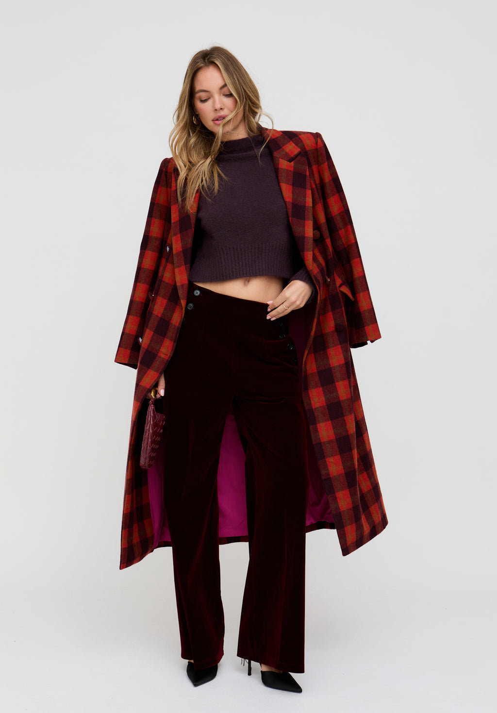 Woman wearing a red plaid coat over a dark outfit on a white background