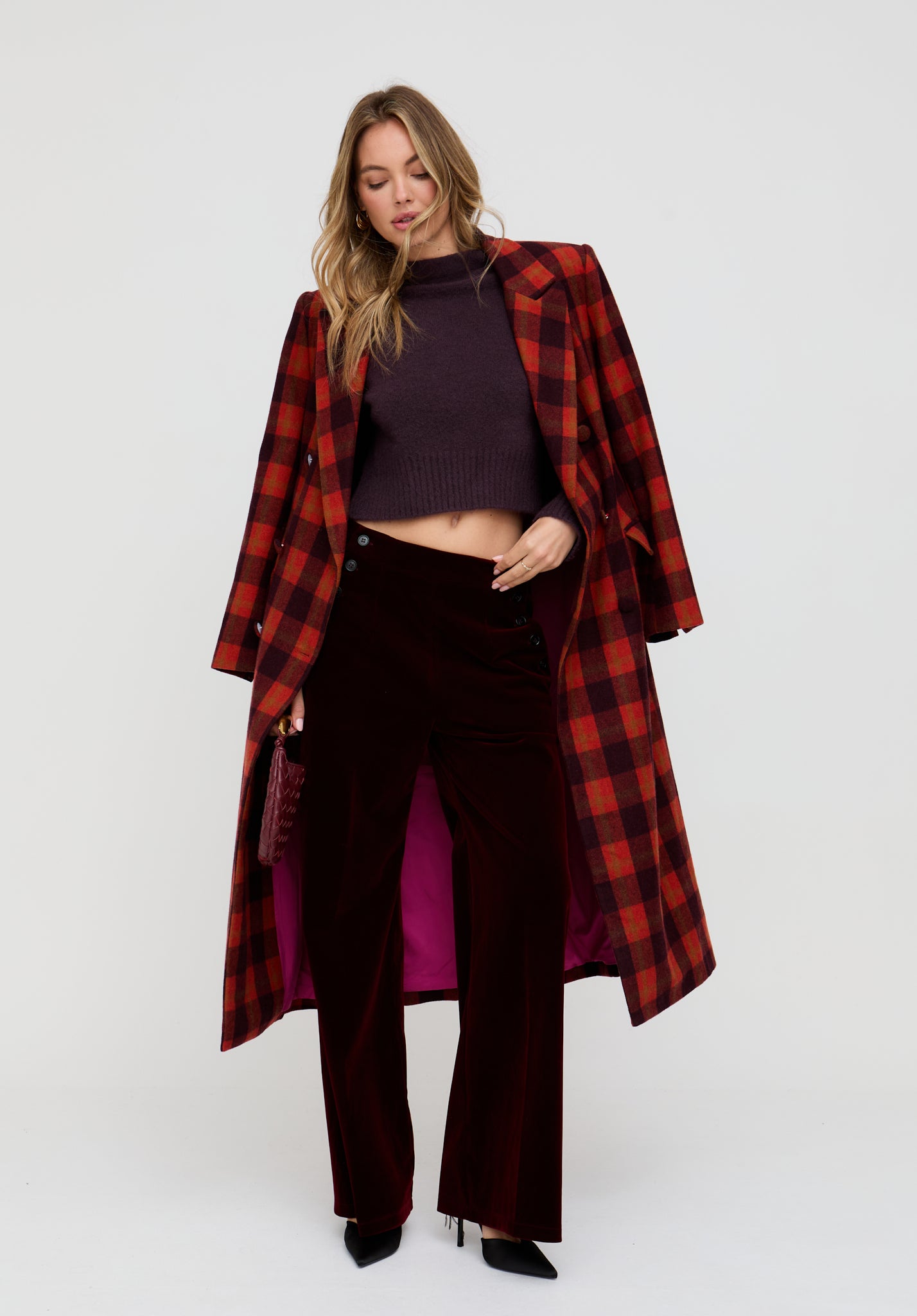 Woman wearing a red plaid coat over a dark outfit on a white background