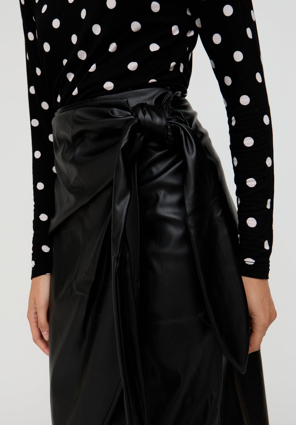 Black polka dot top with a black satin bow on a plain background