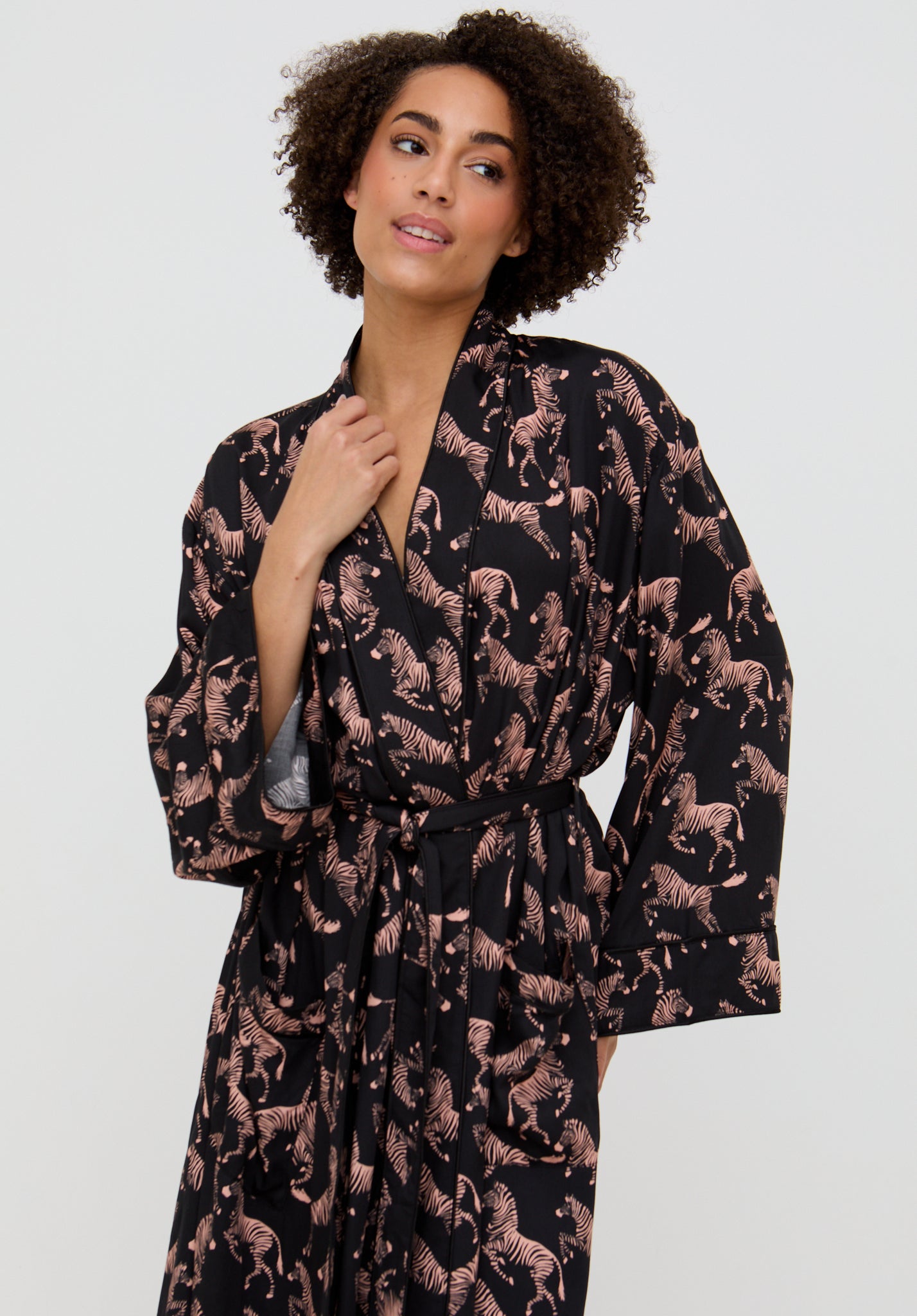 Woman wearing a black robe with pink horse pattern on a white background