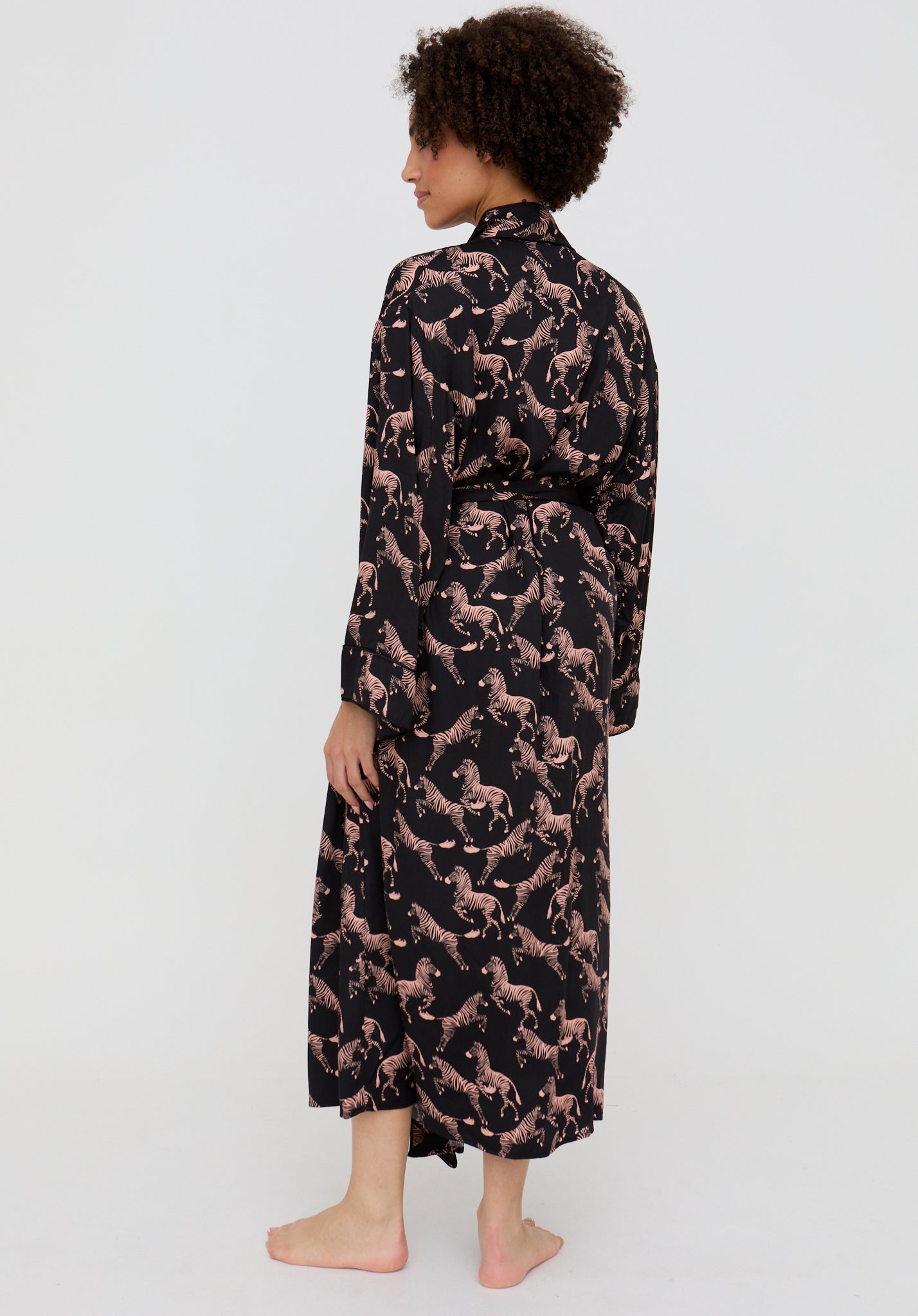 Woman wearing a black dress with pink floral pattern on a white background