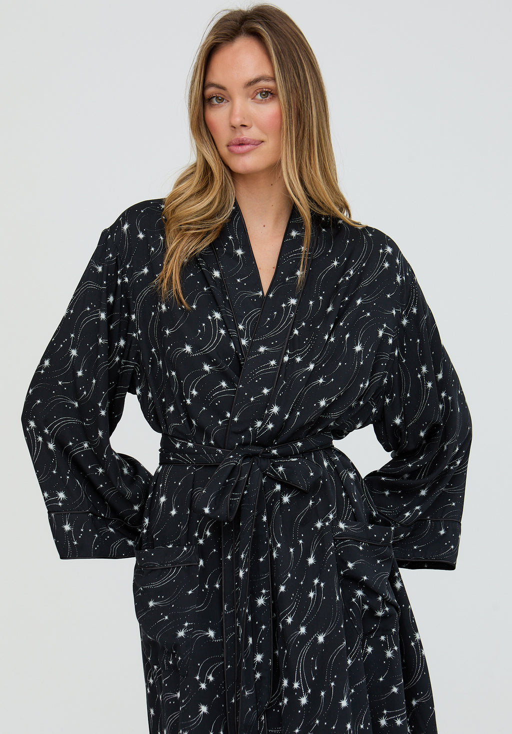 Woman wearing a black robe with white star pattern on a plain background