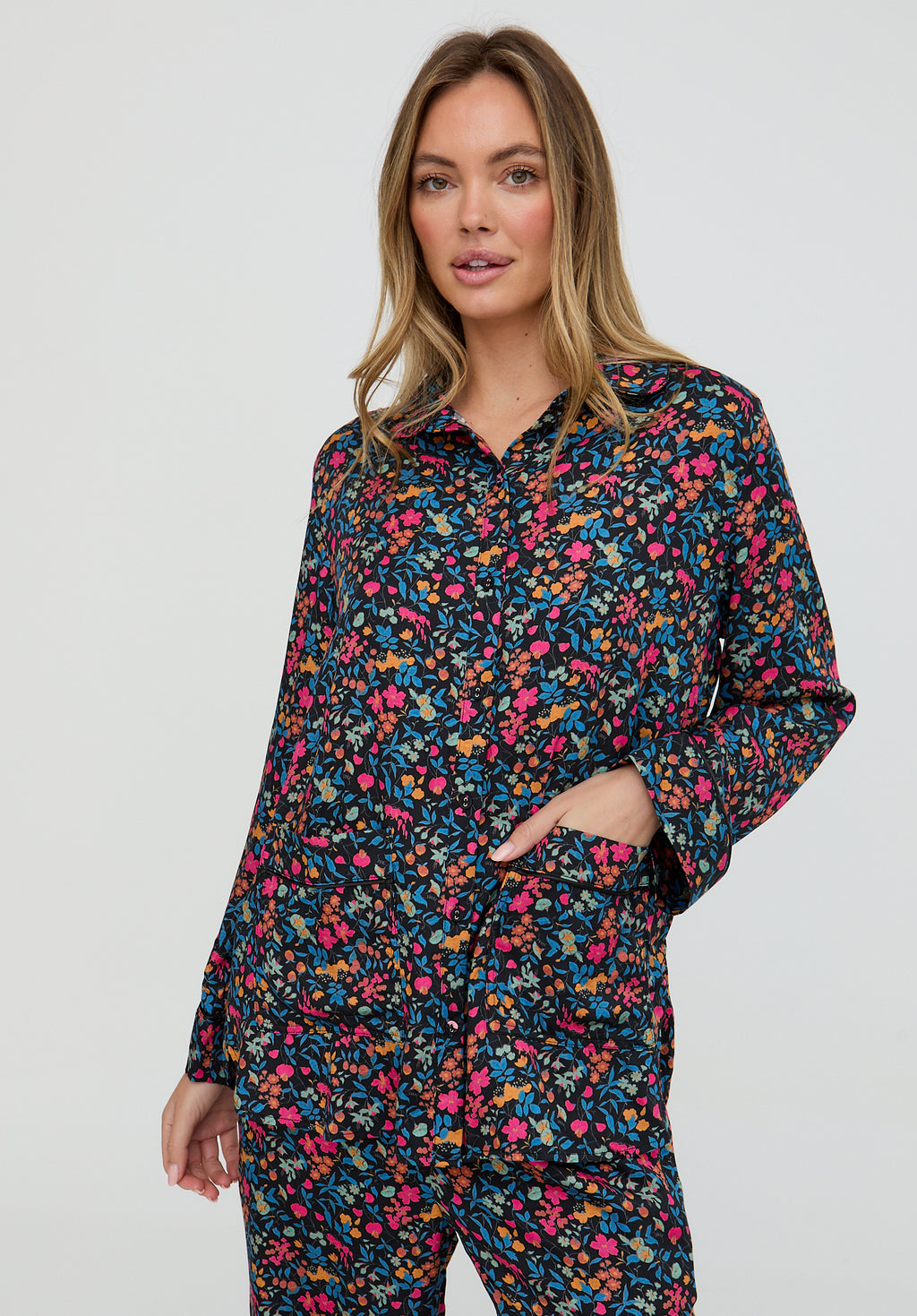 Woman wearing a colorful floral pajama set on a white background