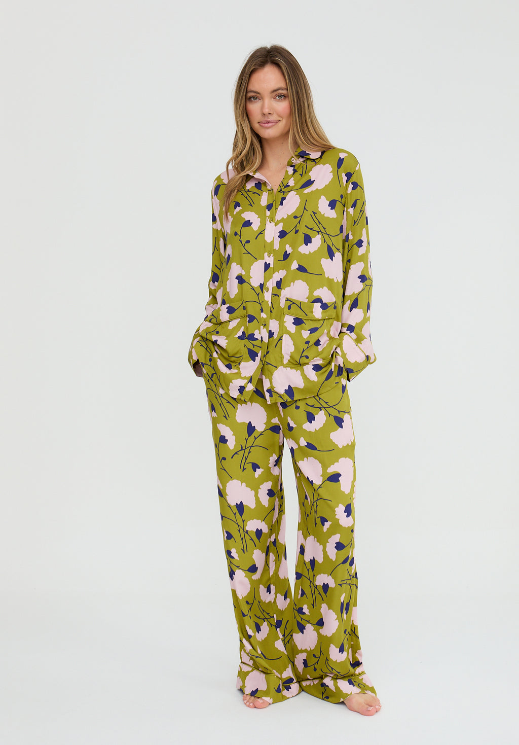 Woman wearing a green floral pajama set on a white background