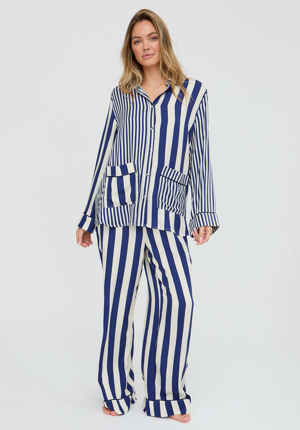 Woman wearing a blue and white striped pajama set on a light gray background