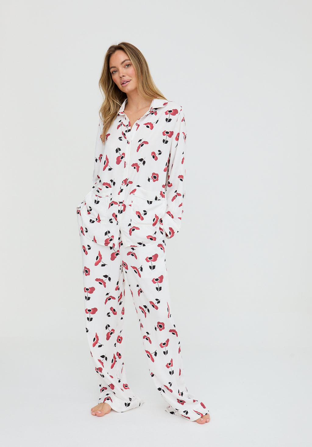 Woman wearing a white onesie with red and black floral pattern on a white background