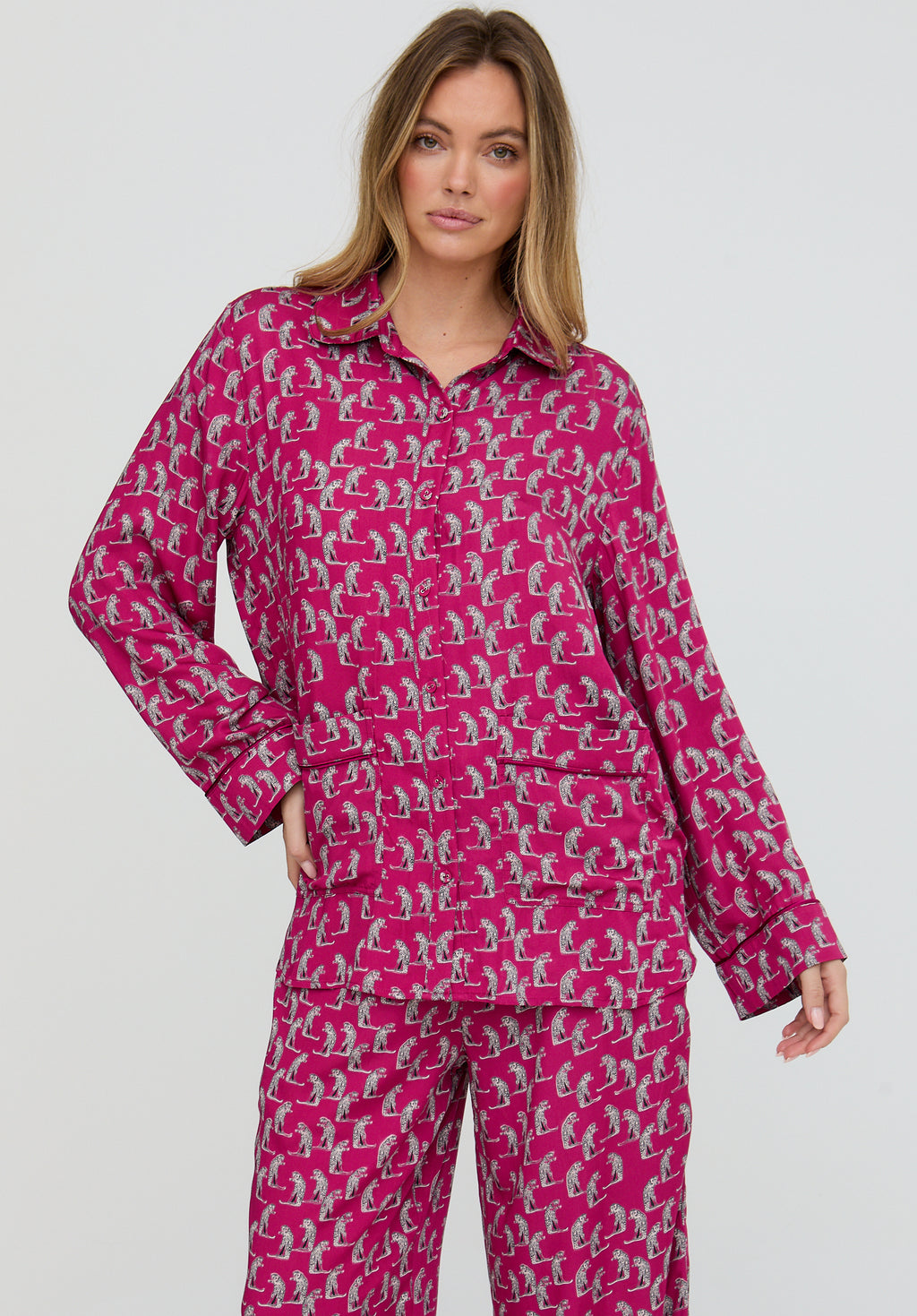 Woman wearing a pink pajama set with a pattern on a white background