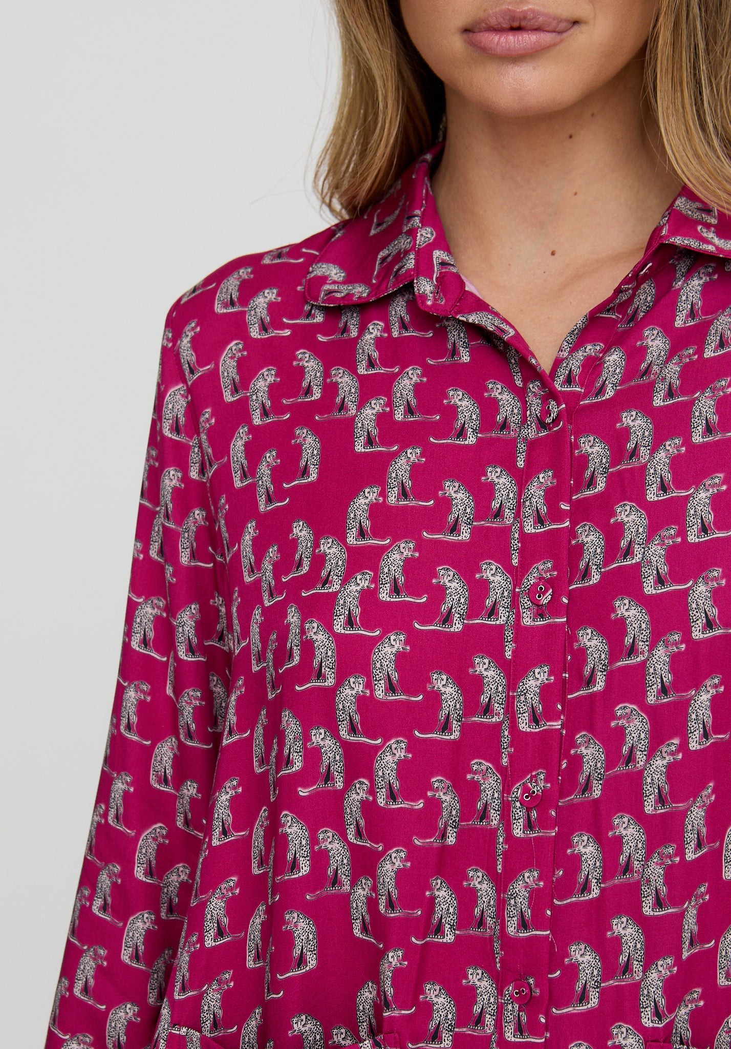 Person wearing a pink shirt with a pattern of people playing golf on a white background